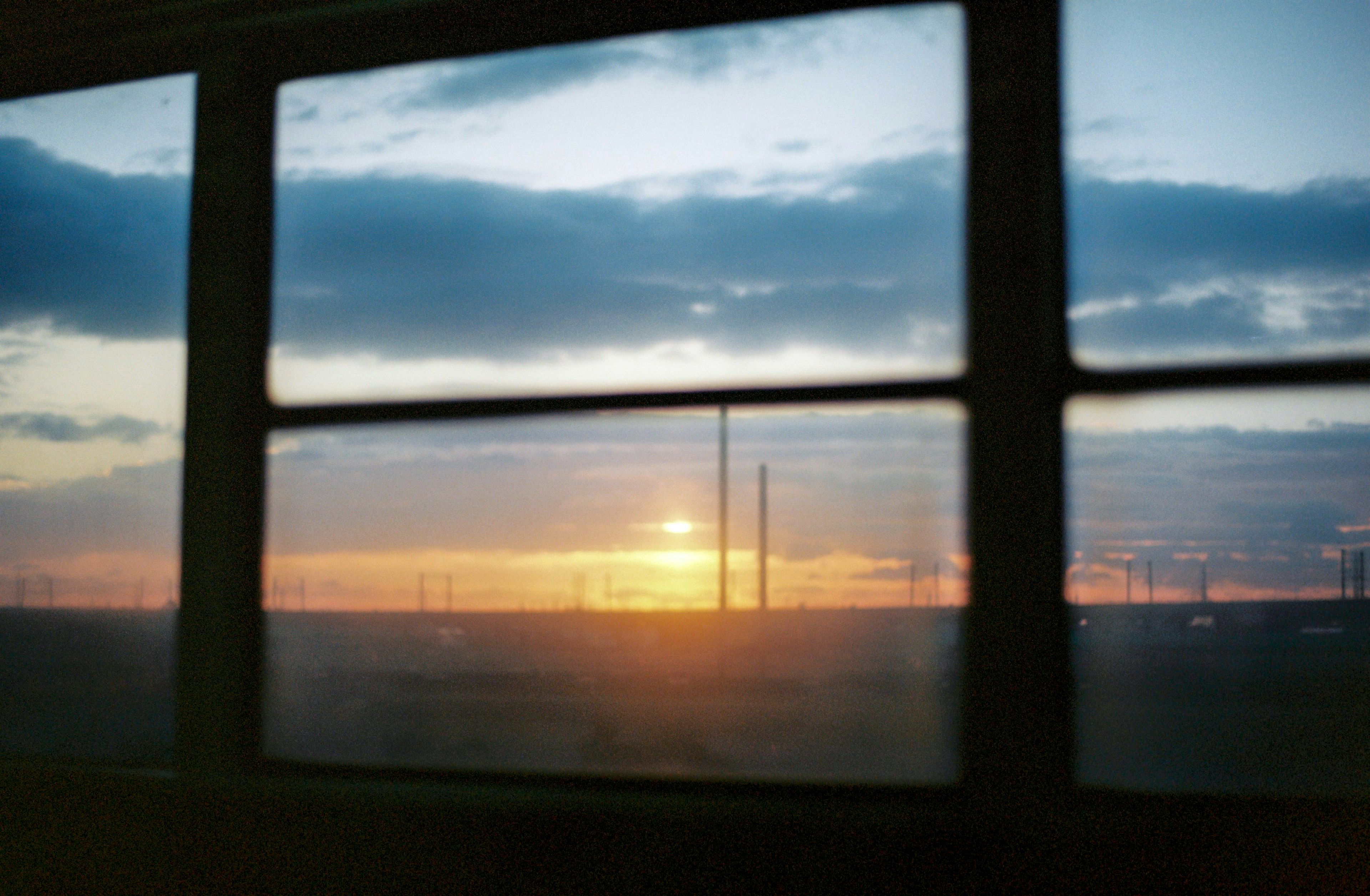 Vue du coucher de soleil à travers une fenêtre avec des nuages