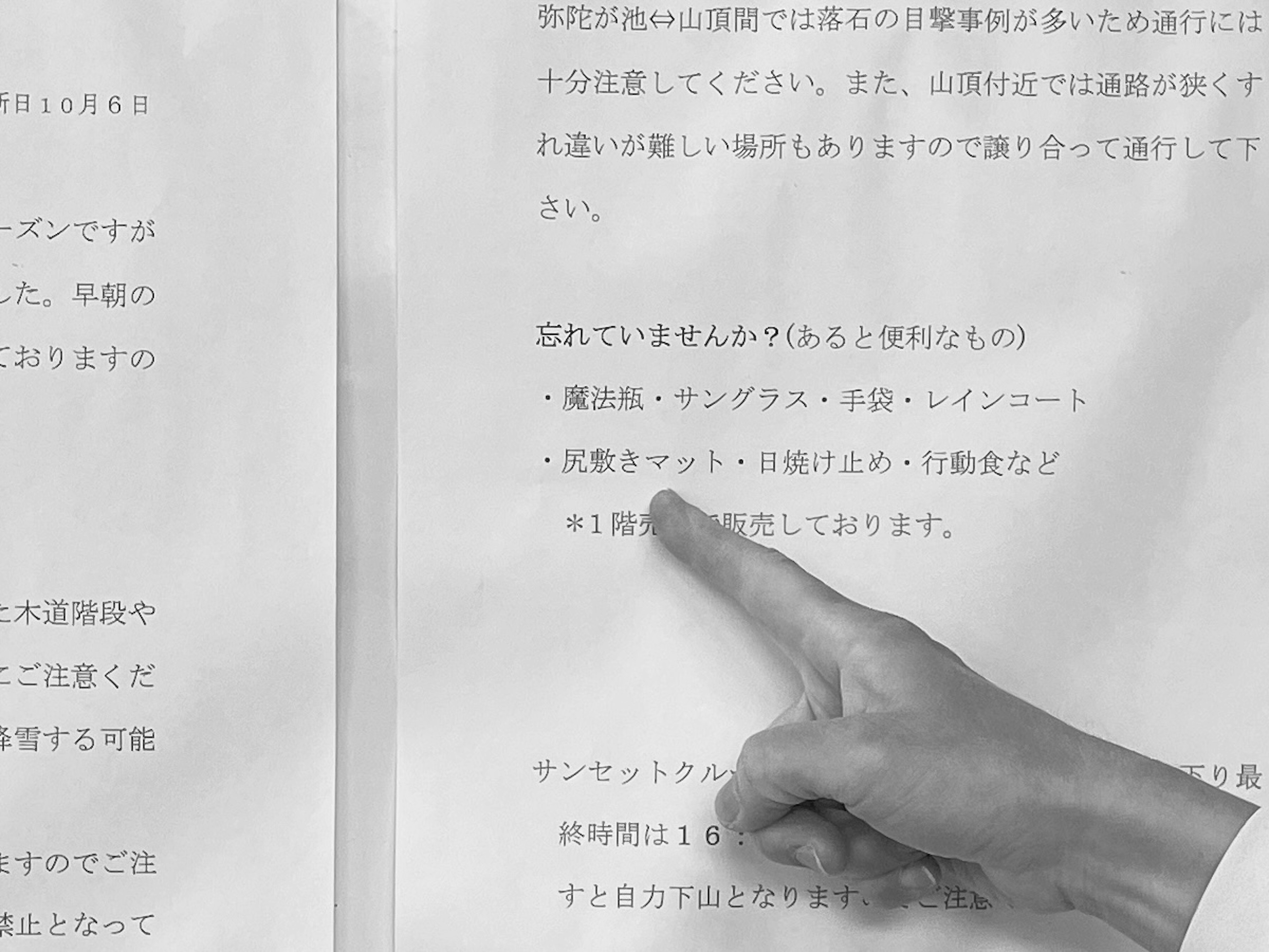 Black and white document with text in Japanese and a finger pointing at the text