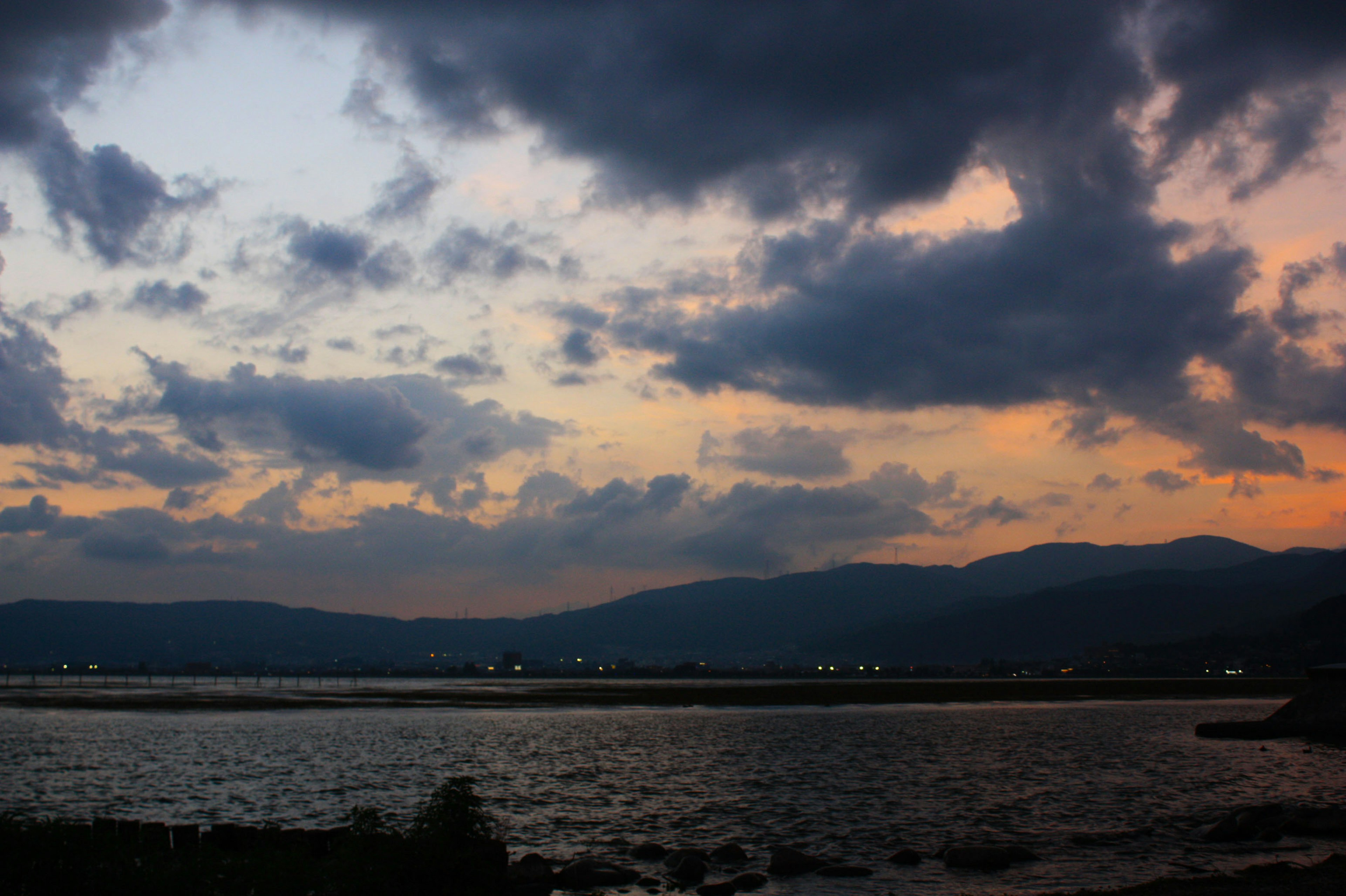 Vista al crepuscolo del mare e delle montagne con un cielo in gradiente arancione e blu