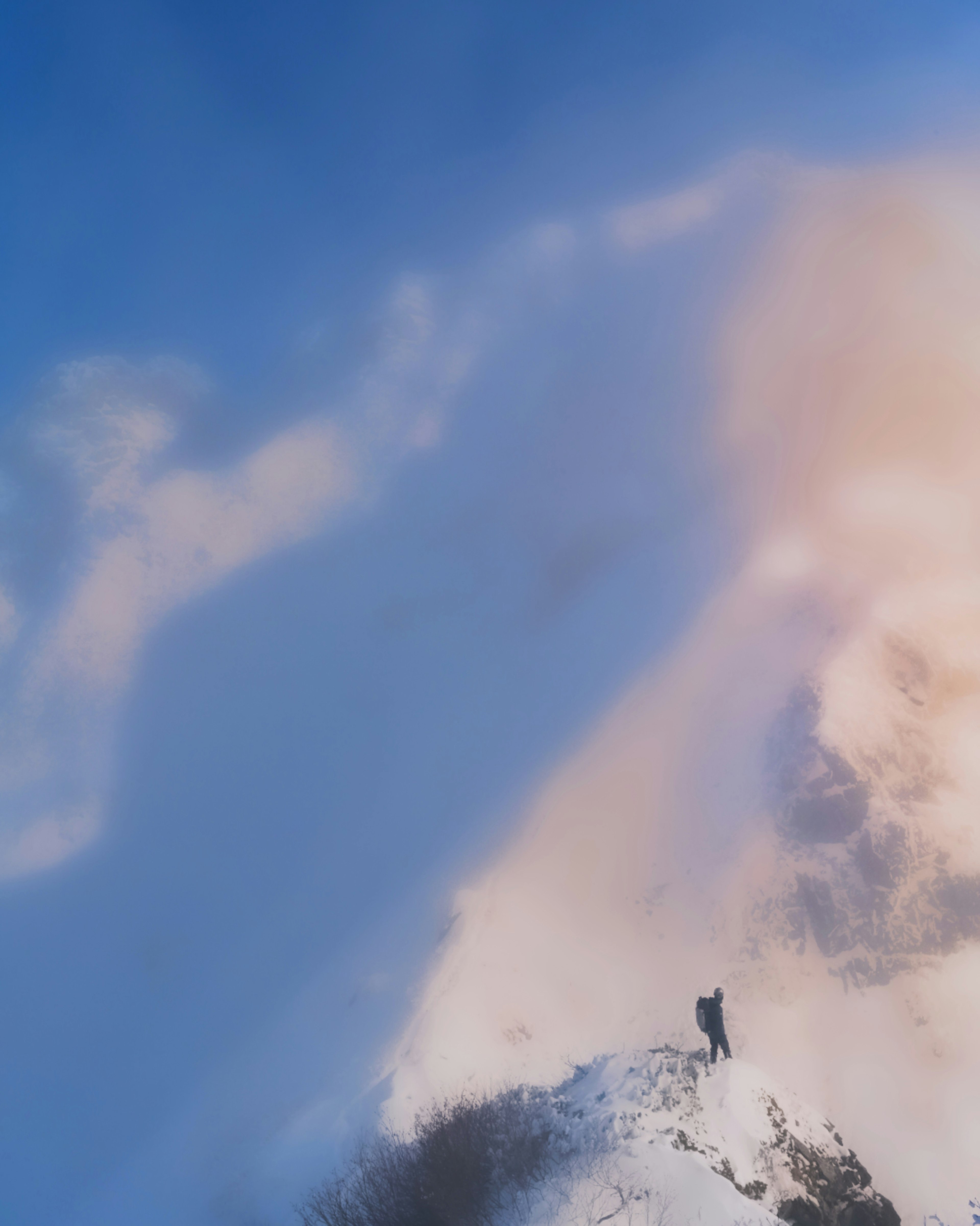 Escalador en una cima nevada bajo un cielo azul