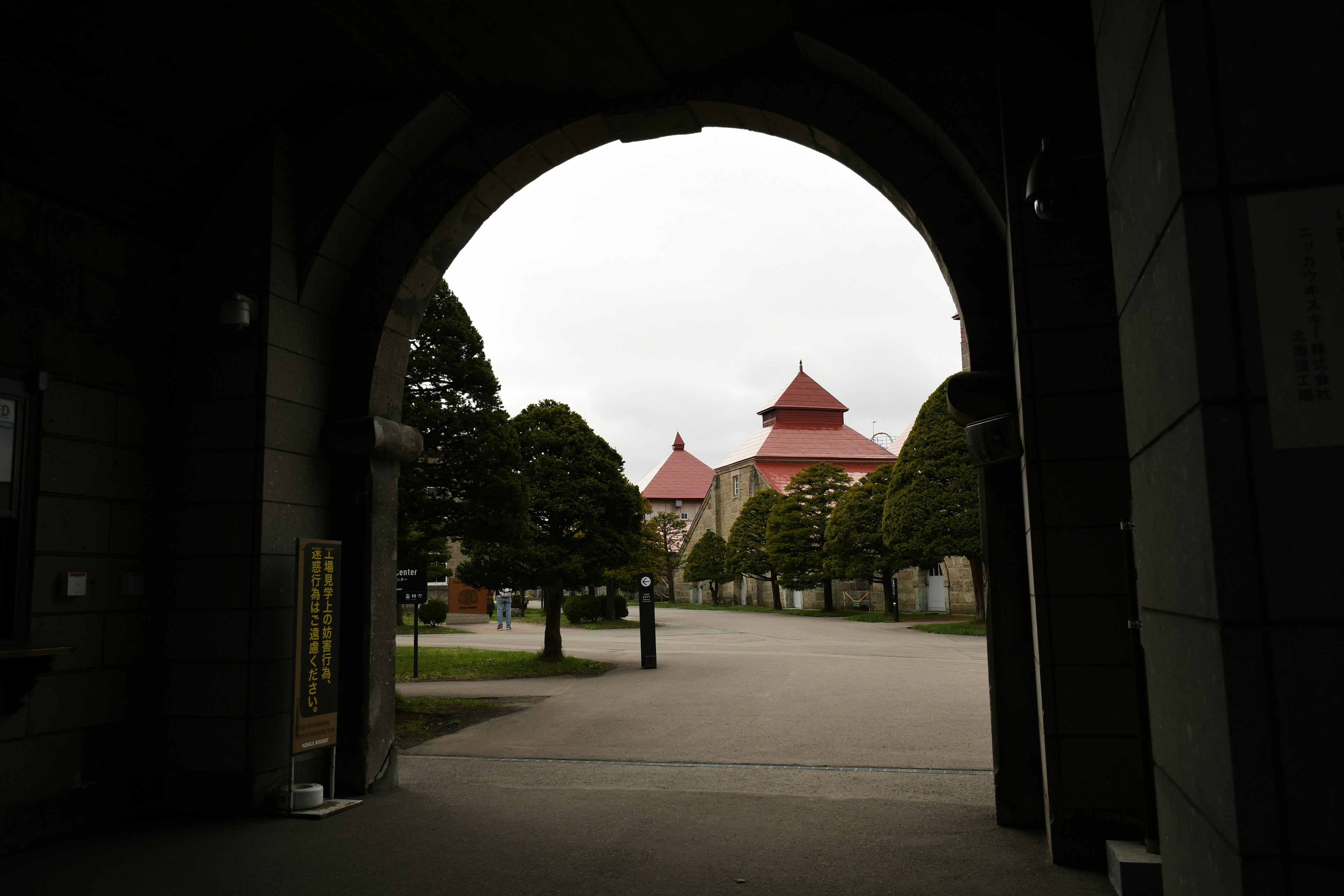 View through an archway showing buildings with red roofs surrounded by trees