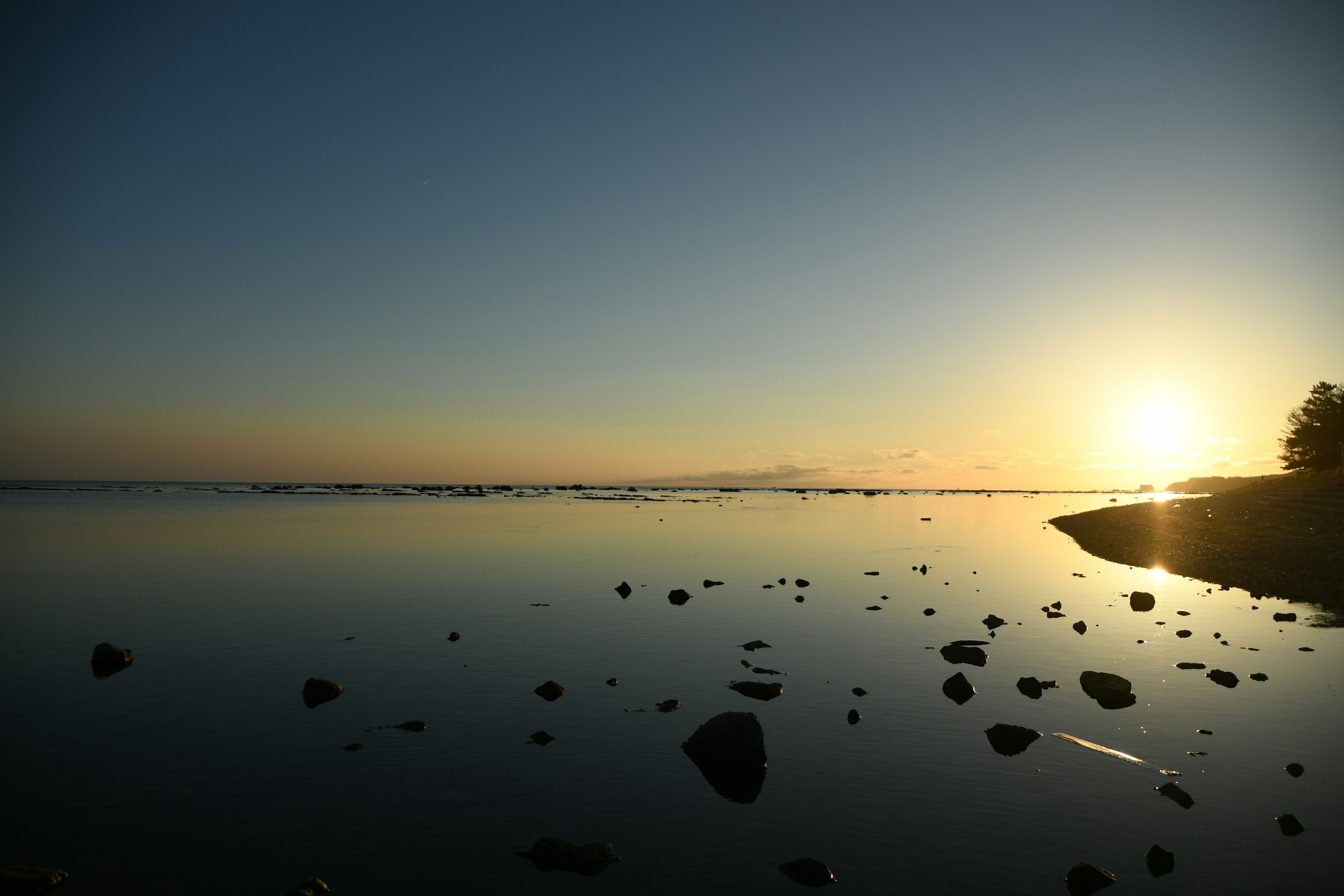 Paesaggio marino sereno con un tramonto che si riflette su acque calme