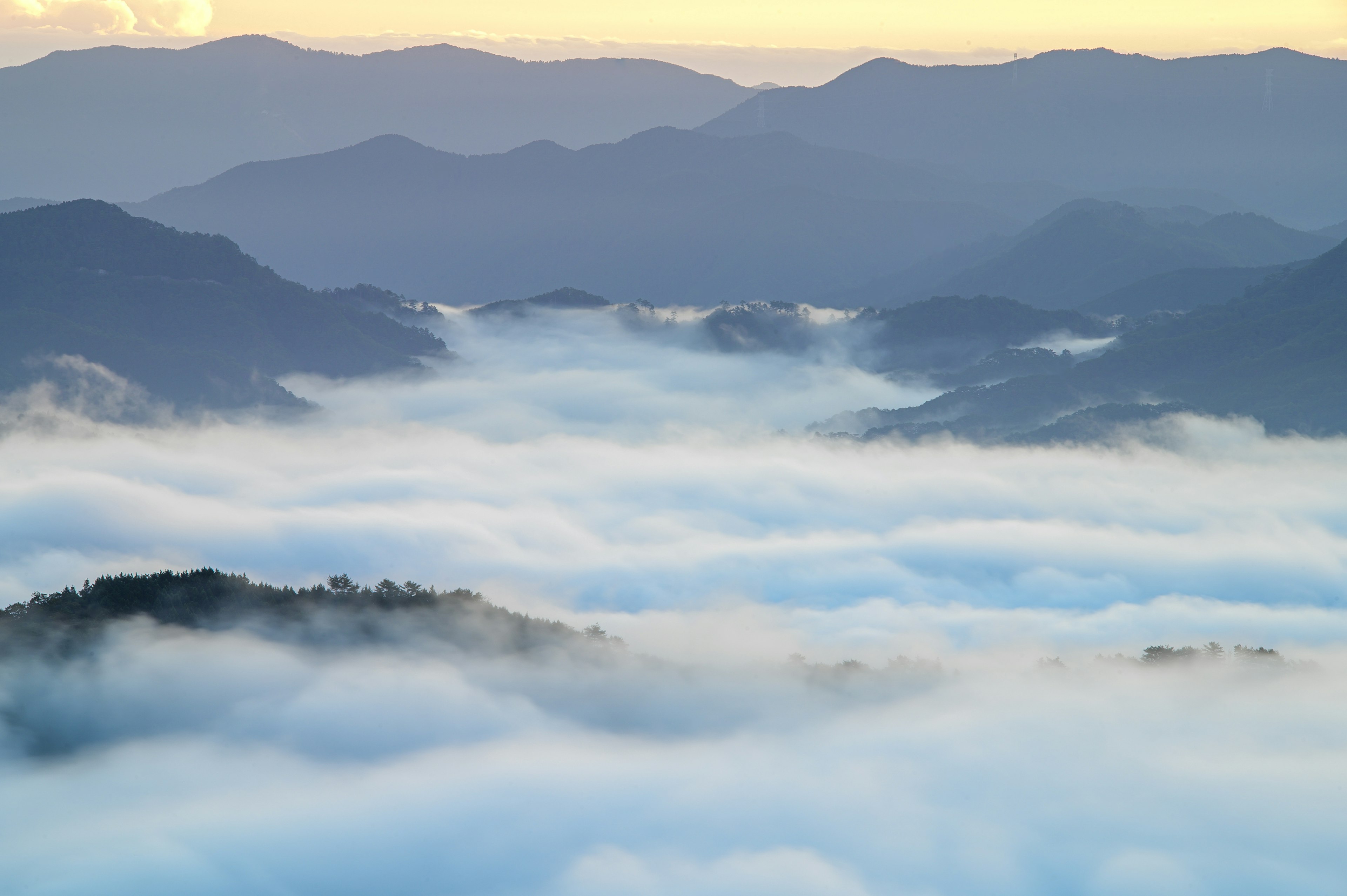 Paysage montagneux enveloppé de brouillard avec un ciel doux au coucher du soleil