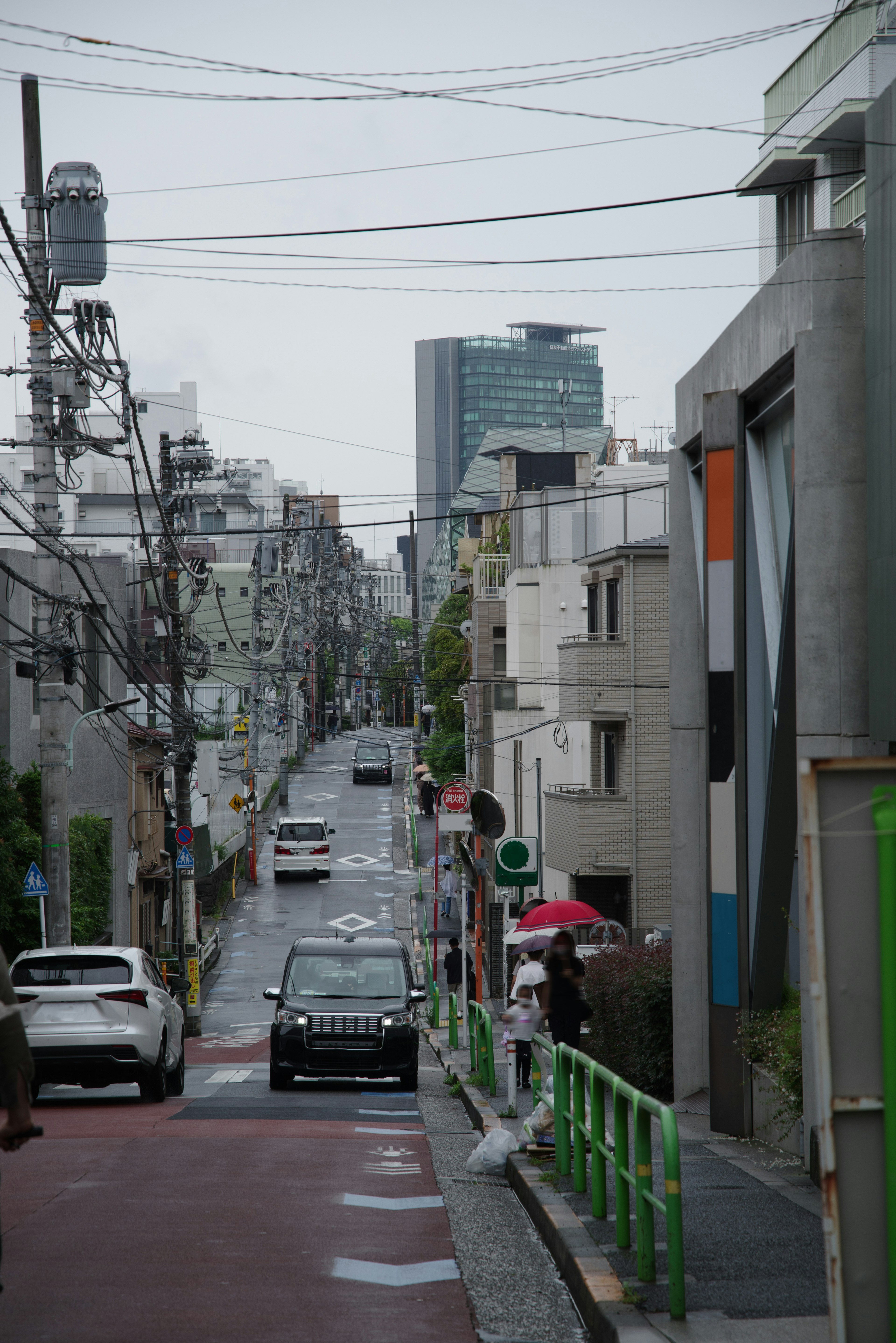 Vista de una calle urbana con edificios residenciales y vehículos con rascacielos de fondo