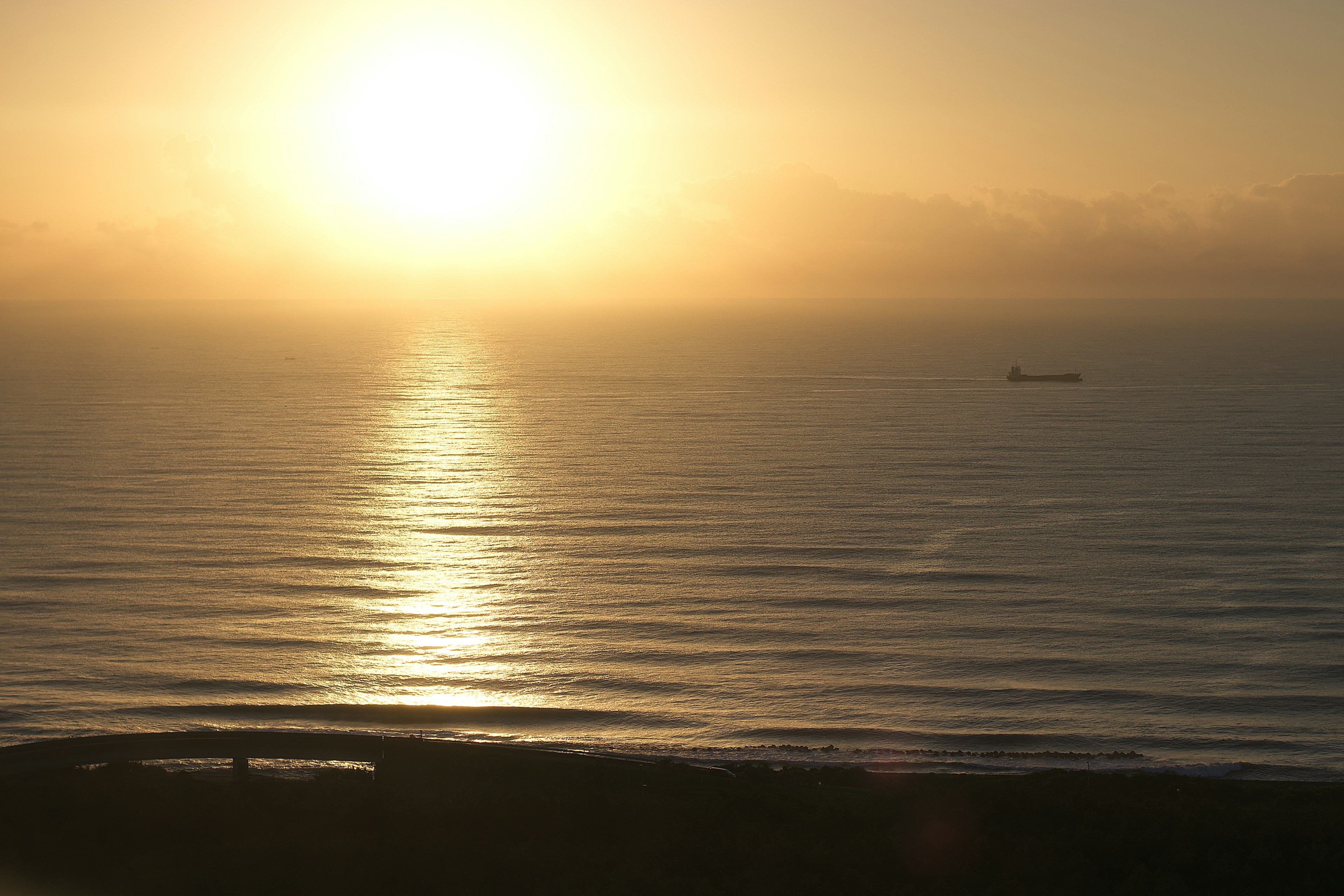 Beautiful view of sunset reflecting on the ocean with a distant ship