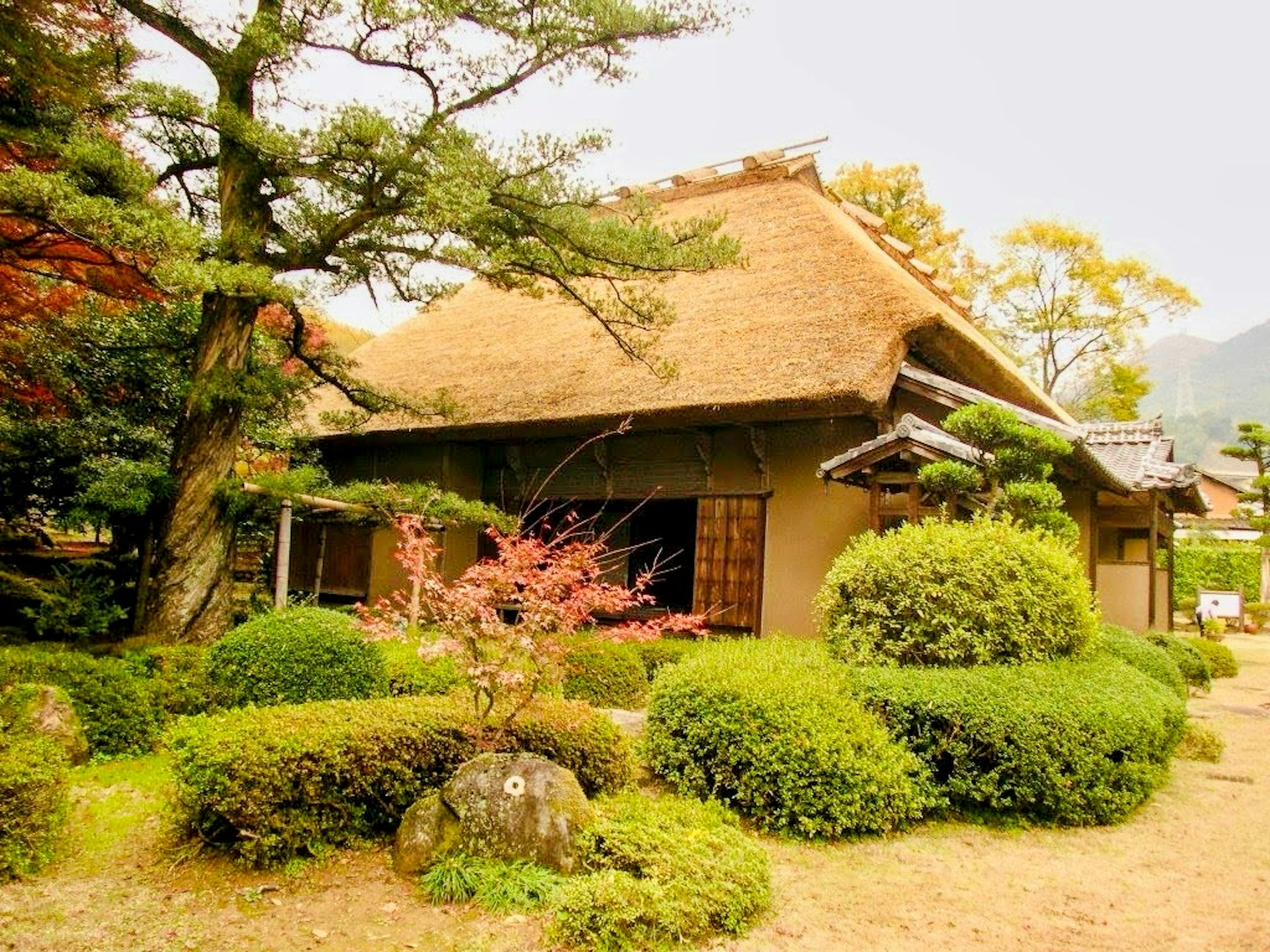 Casa japonesa tradicional con techo de paja y jardín paisajístico