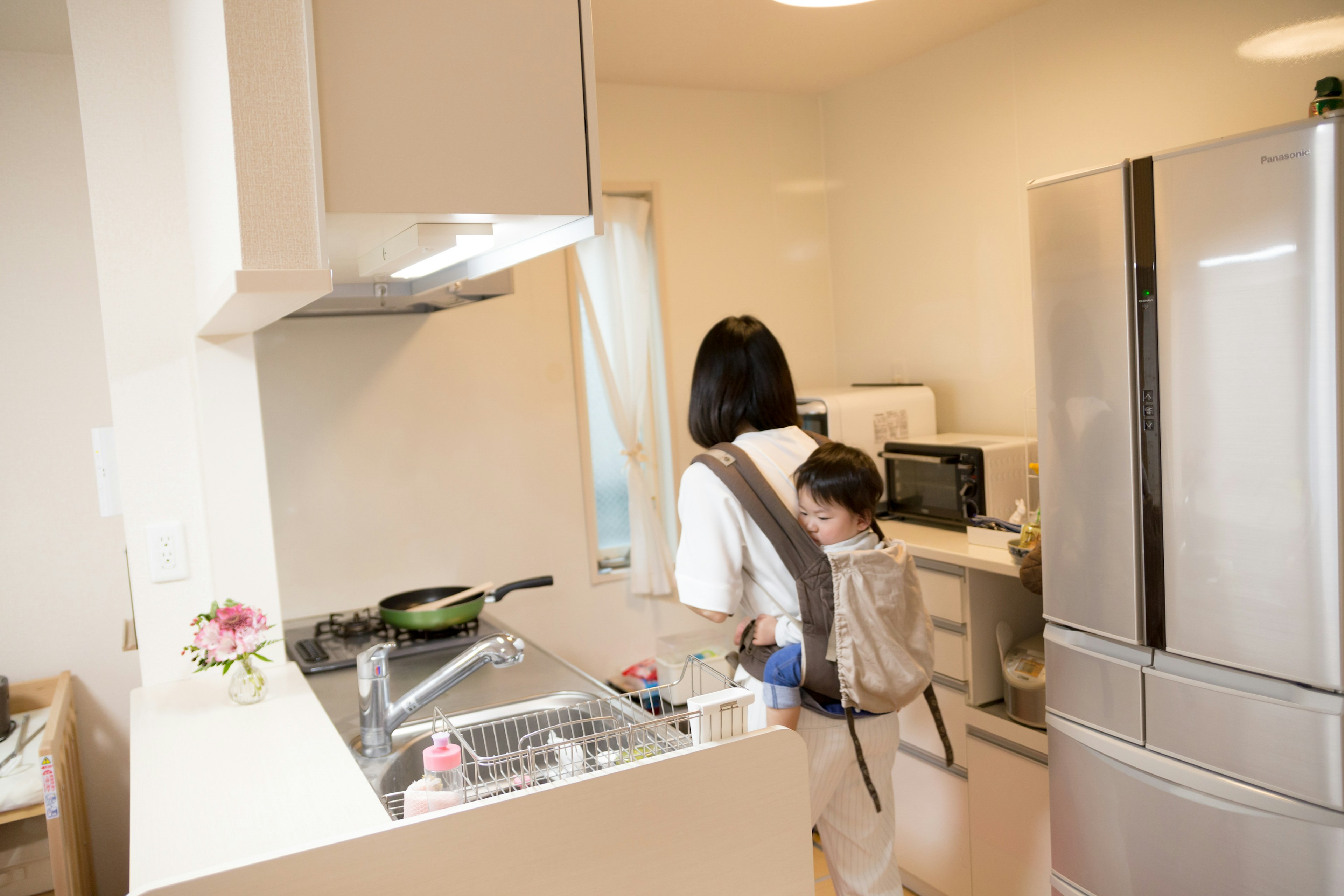 Una madre cocinando en una cocina brillante con un niño en la espalda