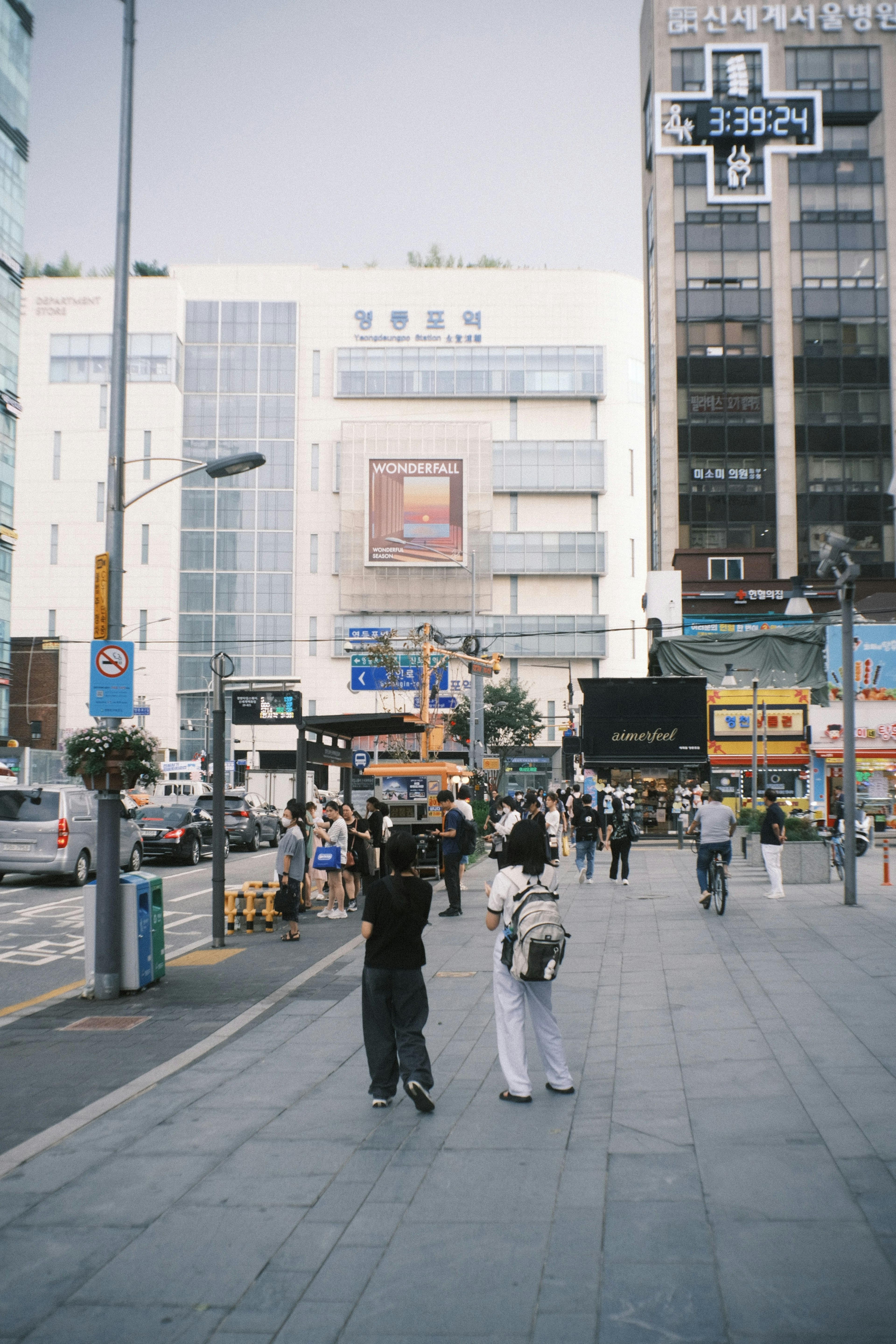 兩個人在城市街道上行走，周圍有繁忙的商店