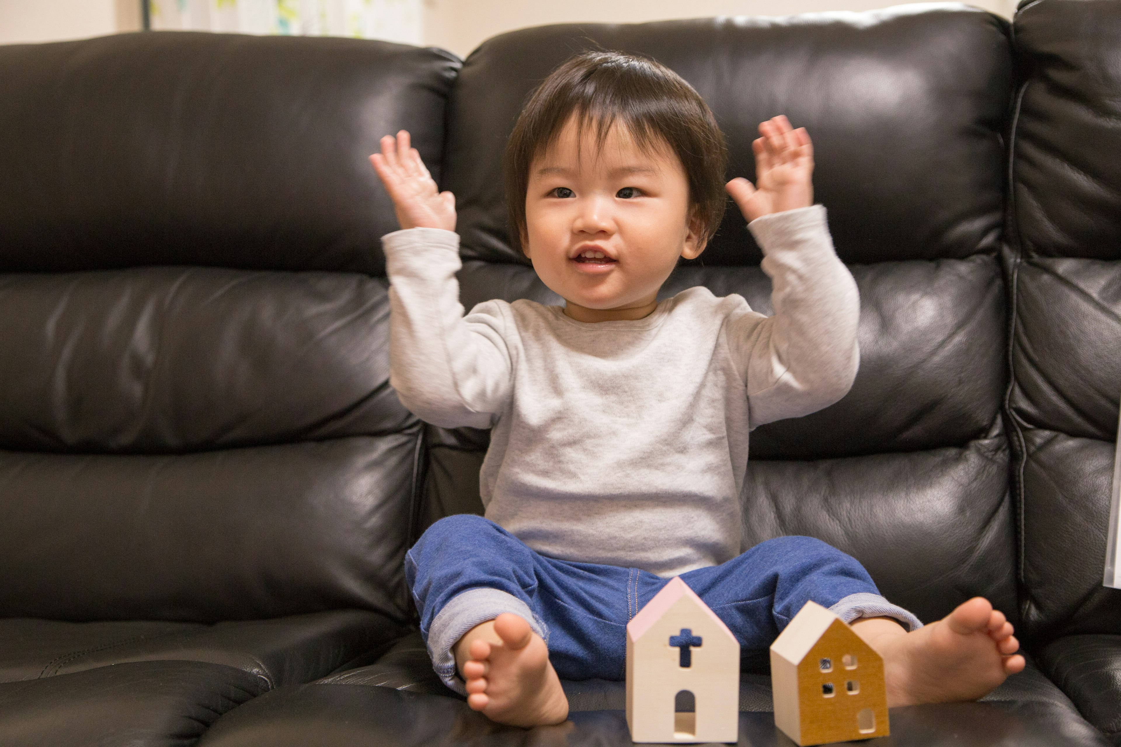 坐在沙發上的幼兒微笑著舉起雙手