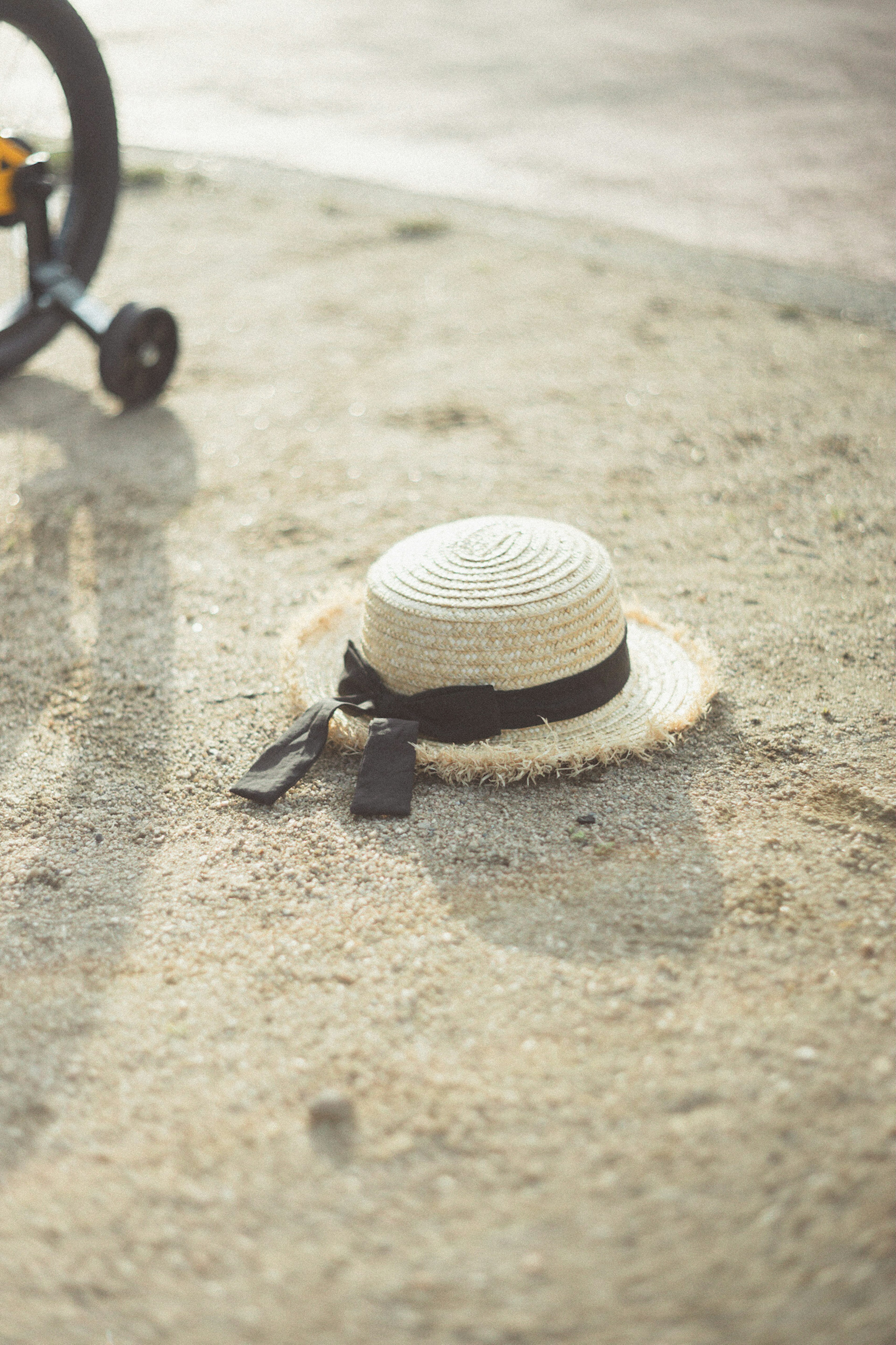 Sombrero de paja con cinta negra colocado sobre el suelo arenoso