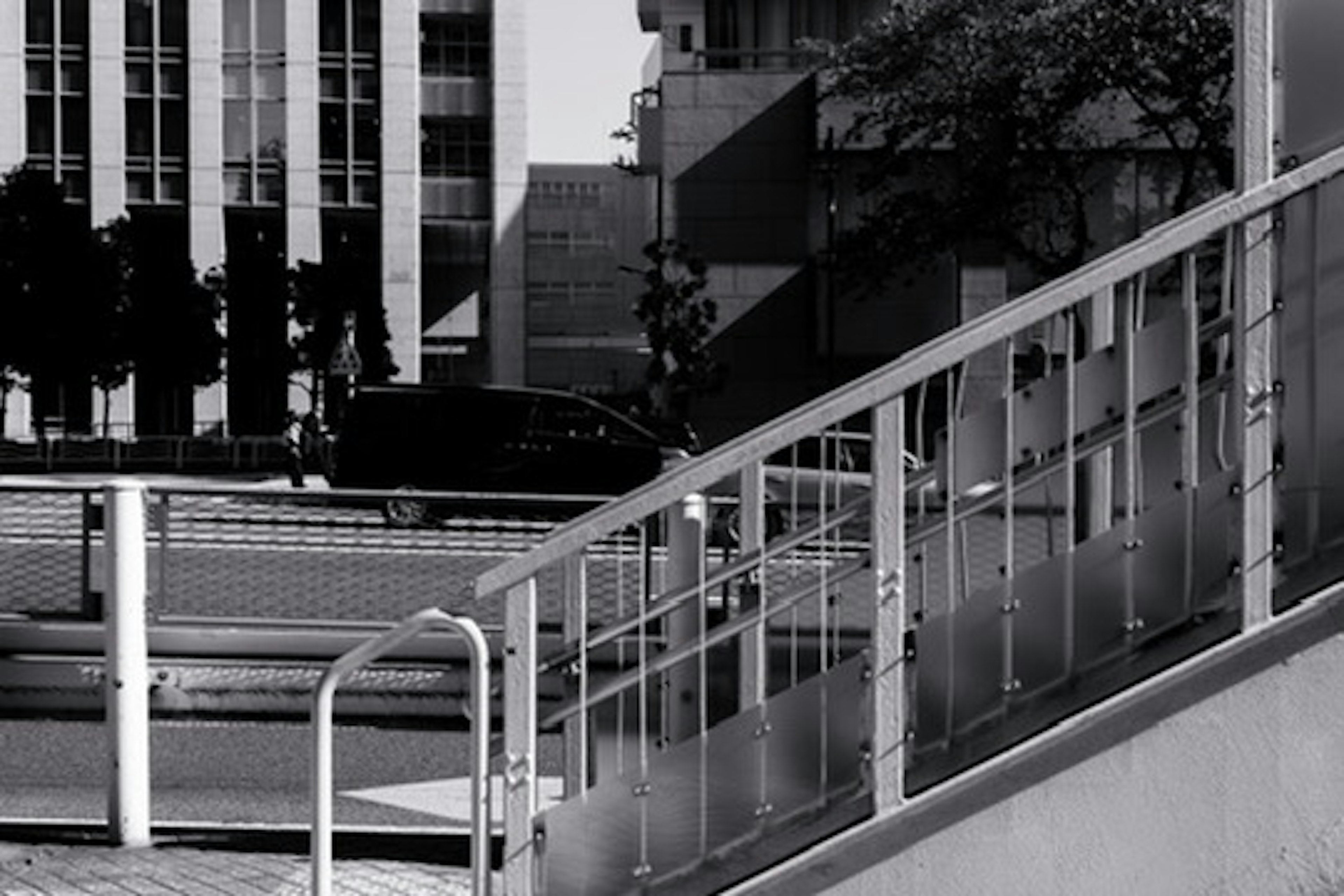 Scène urbaine en noir et blanc avec un escalier et une rampe en verre