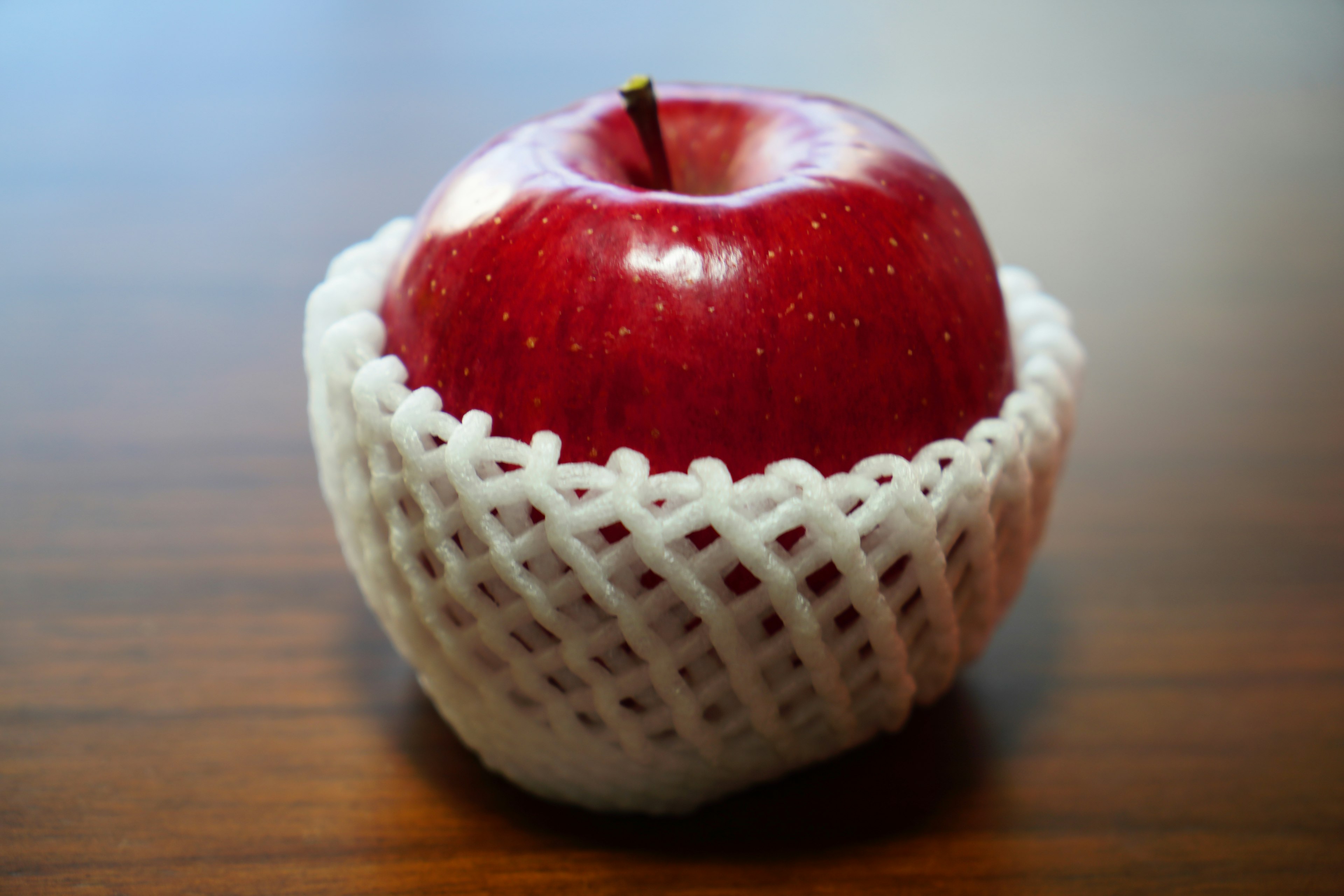 Red apple wrapped in a white mesh netting