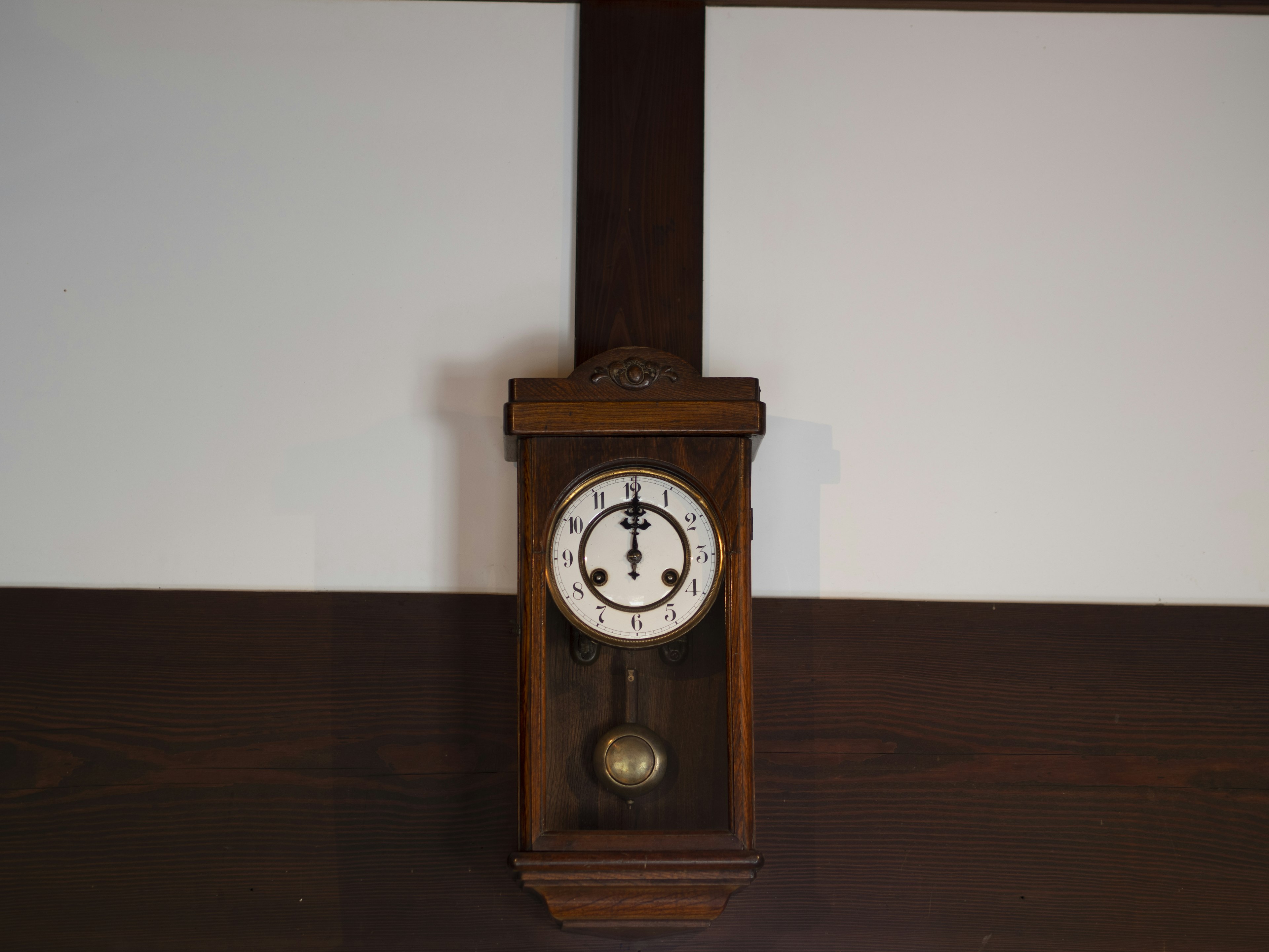 Wooden wall clock with white dial and golden pendulum