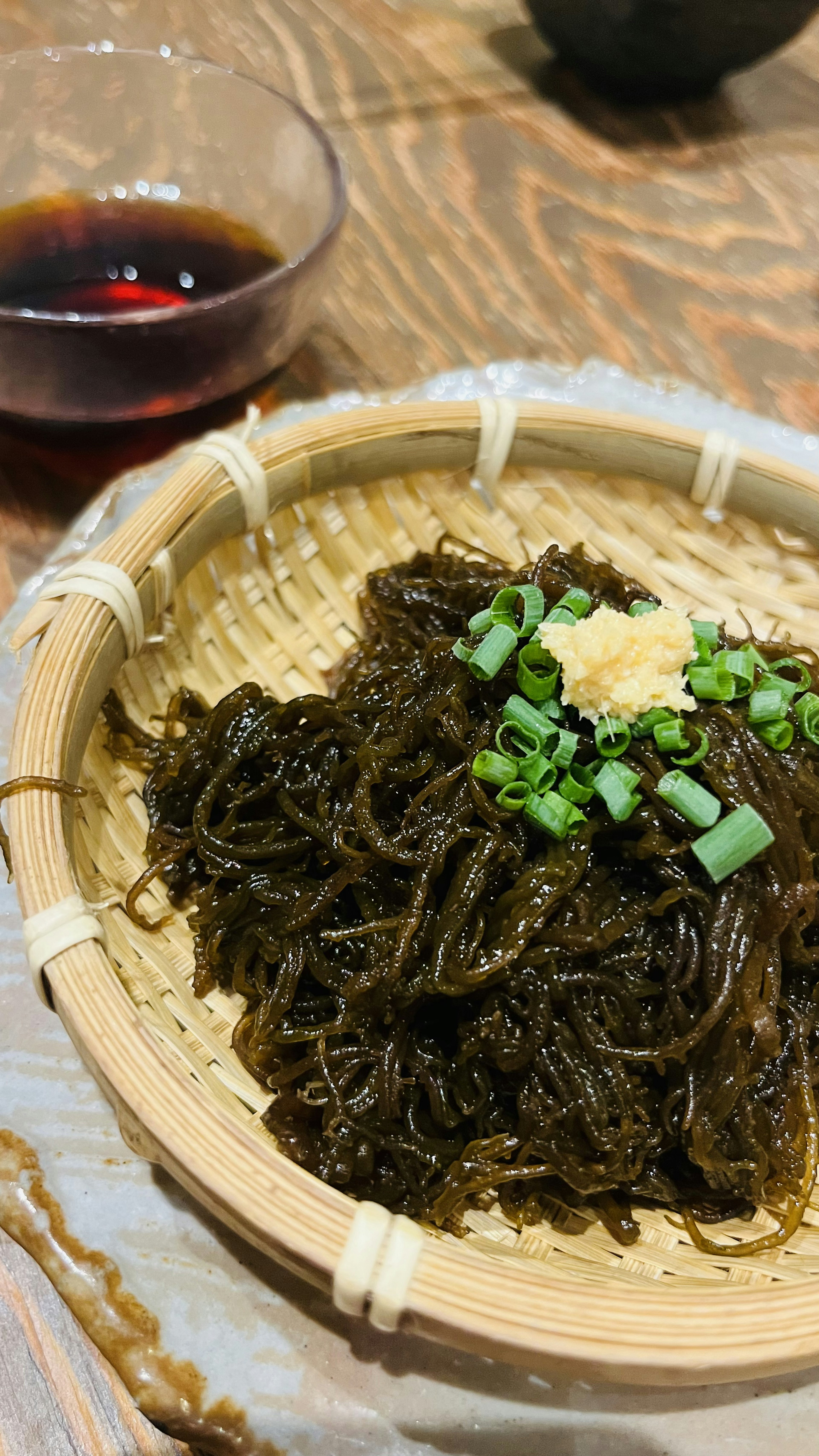 Seaweed salad with finely chopped green onions and ginger topping served in a bamboo basket