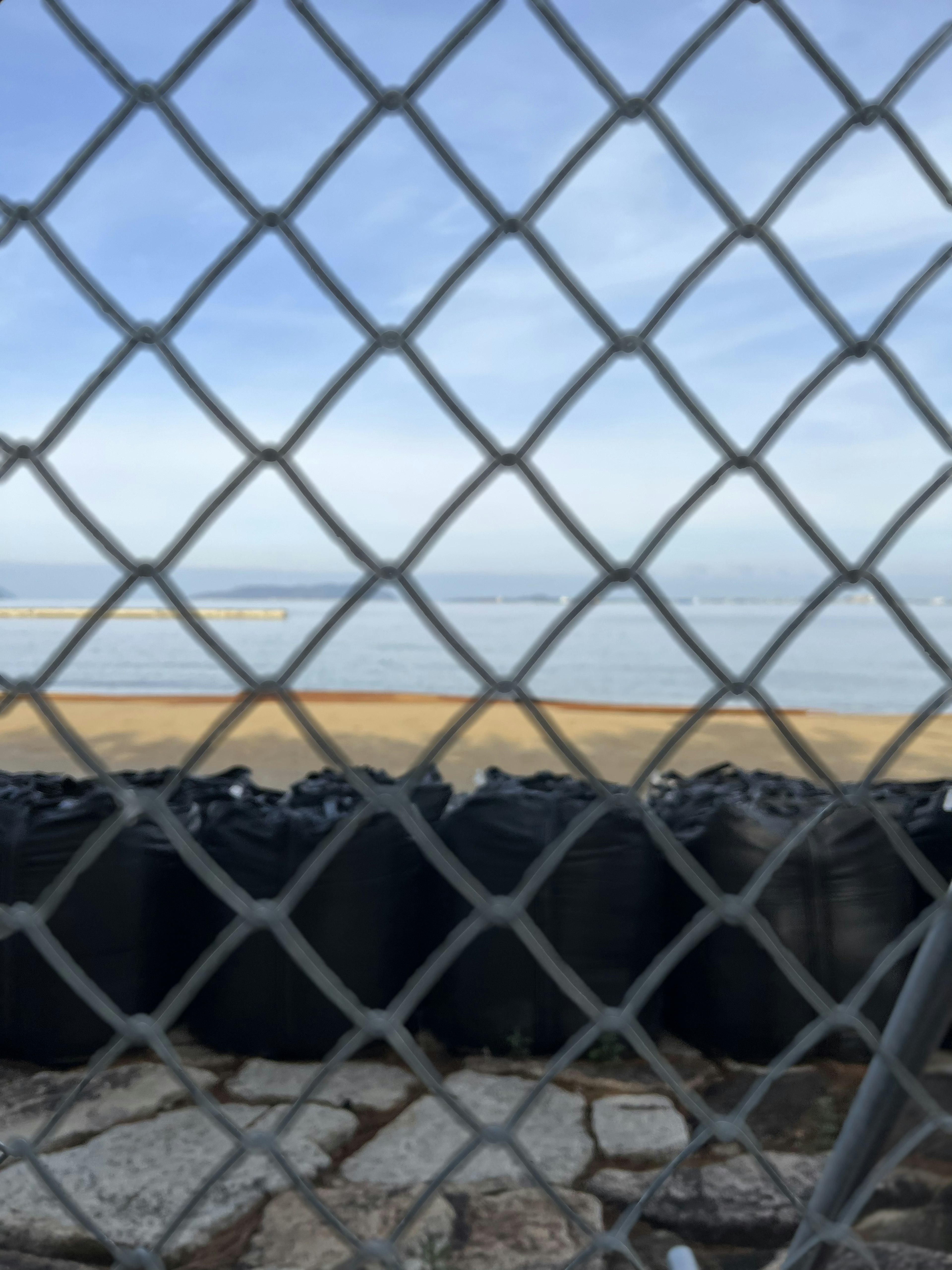 Vista de la playa y el océano a través de una cerca de malla