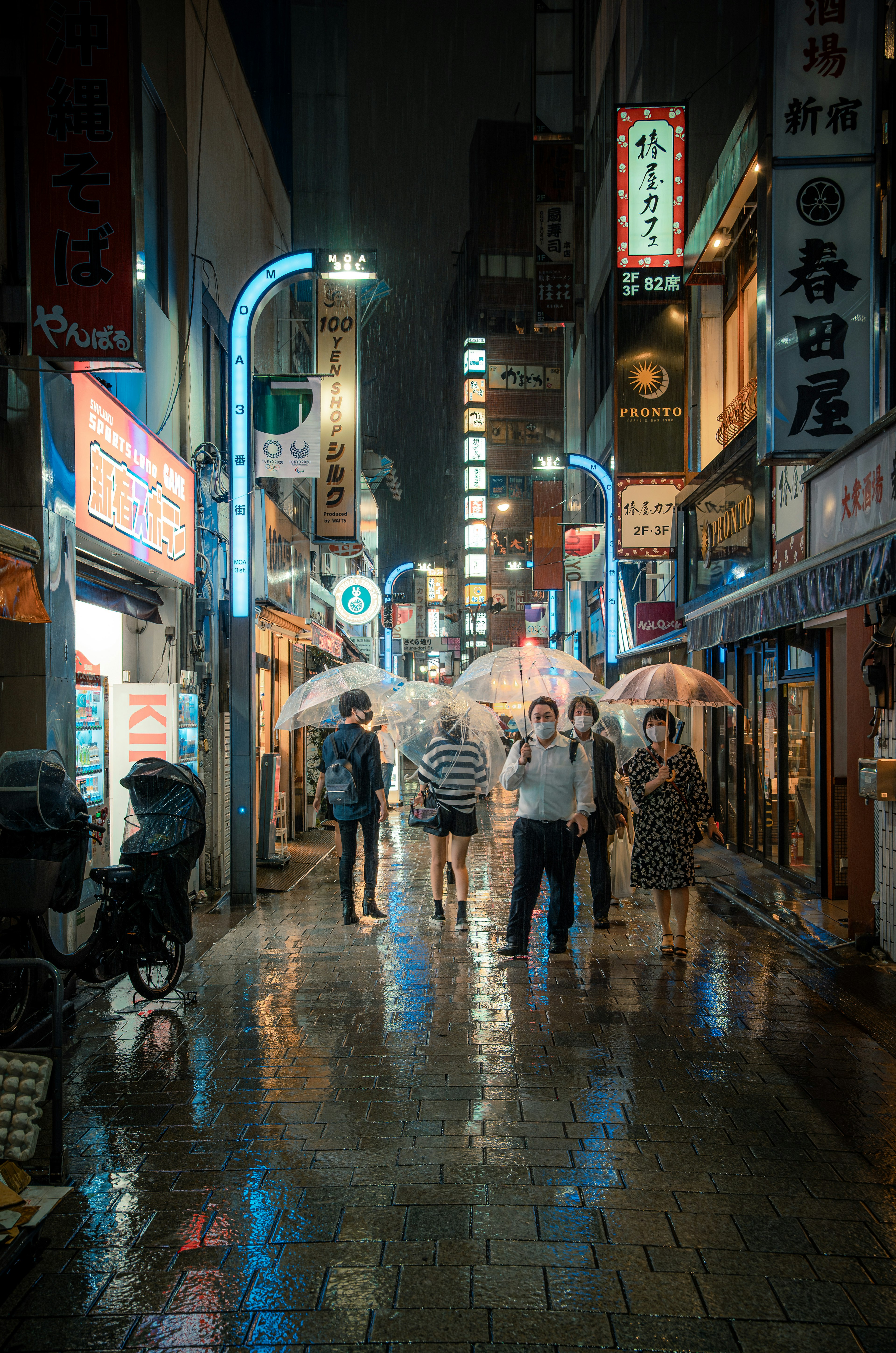 雨の中で傘を持った人々が歩く夜の街並み