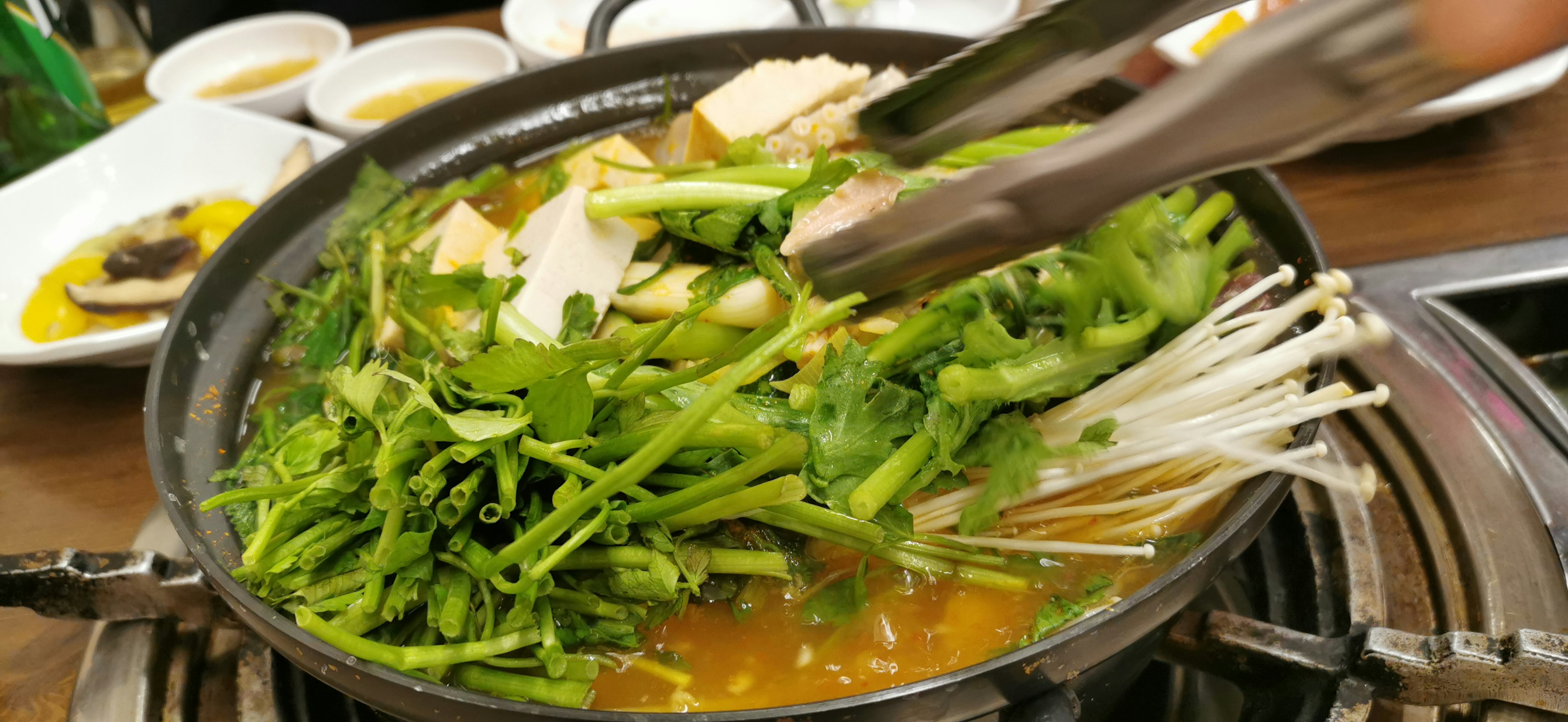 Hot pot with fresh vegetables and tofu being served