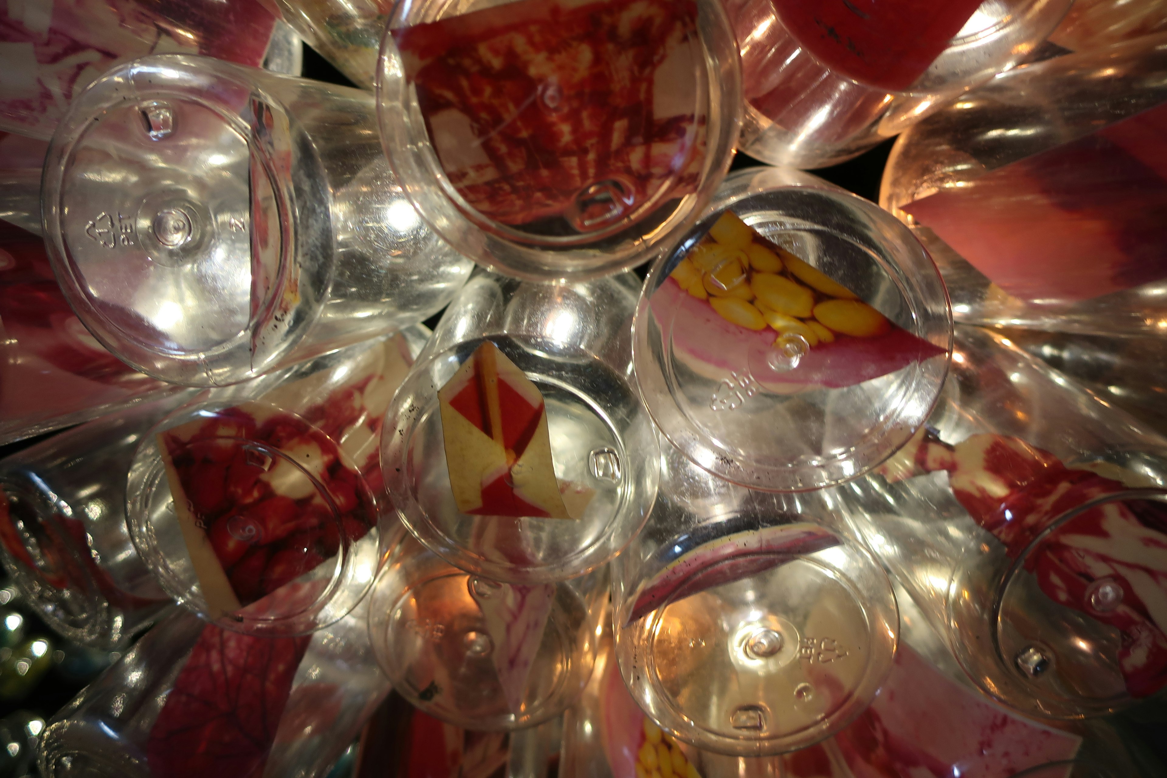 An overhead view of transparent cups illuminated by light showcasing colorful fruit and decorations inside