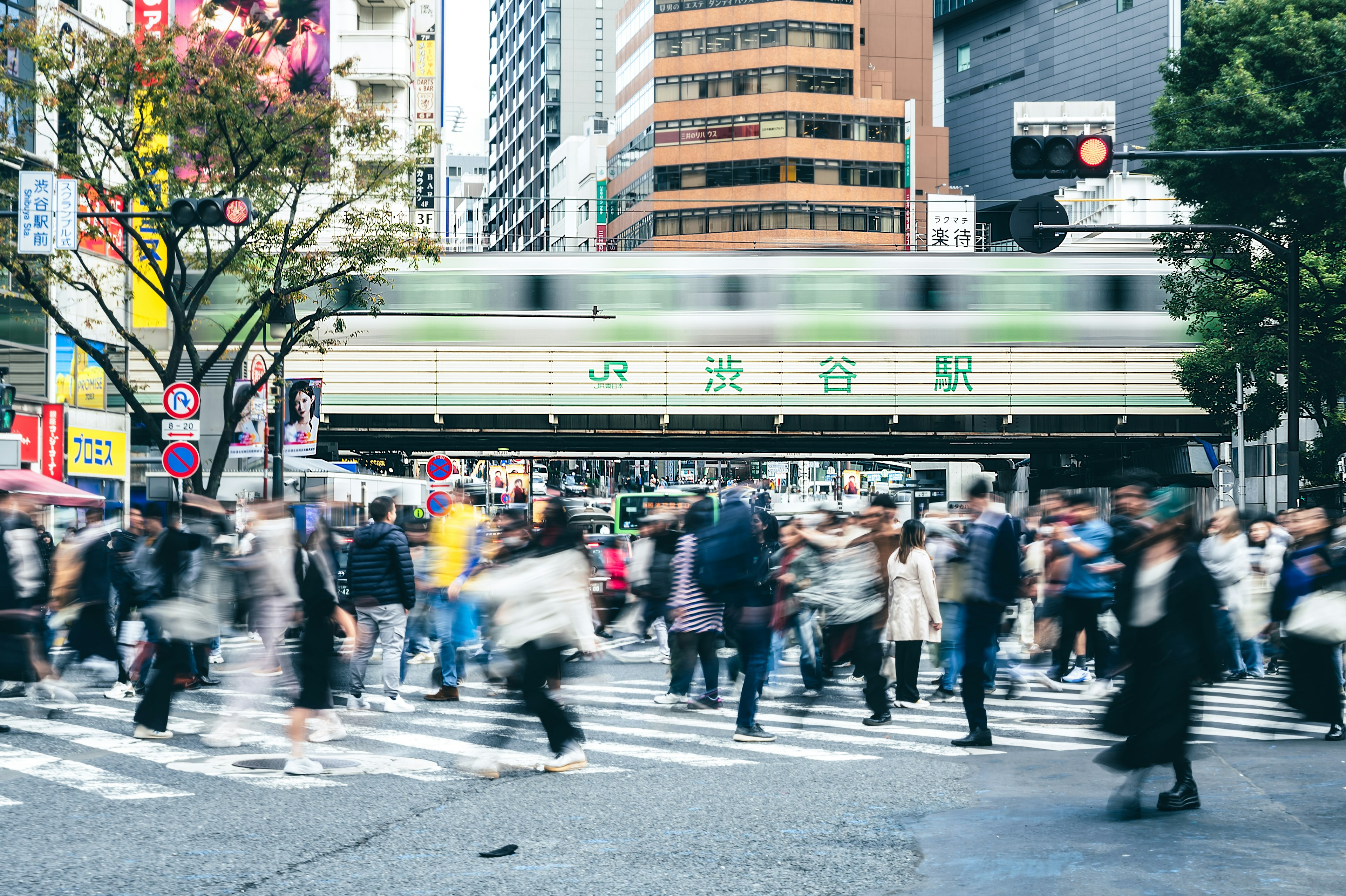 東京の交差点で多くの人々が行き交う様子と流れる電車