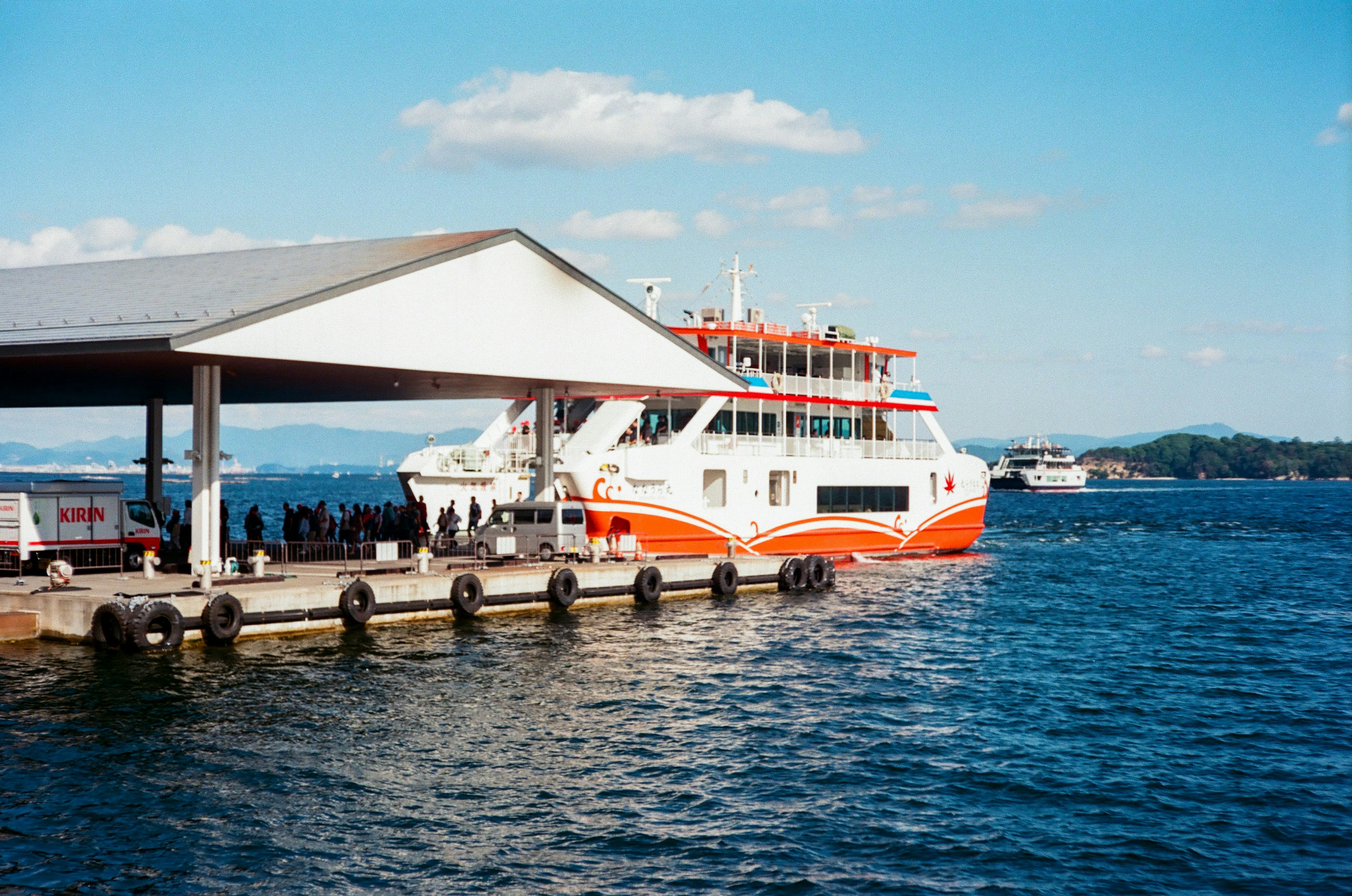 Ferry màu cam và trắng neo tại cảng dưới bầu trời xanh