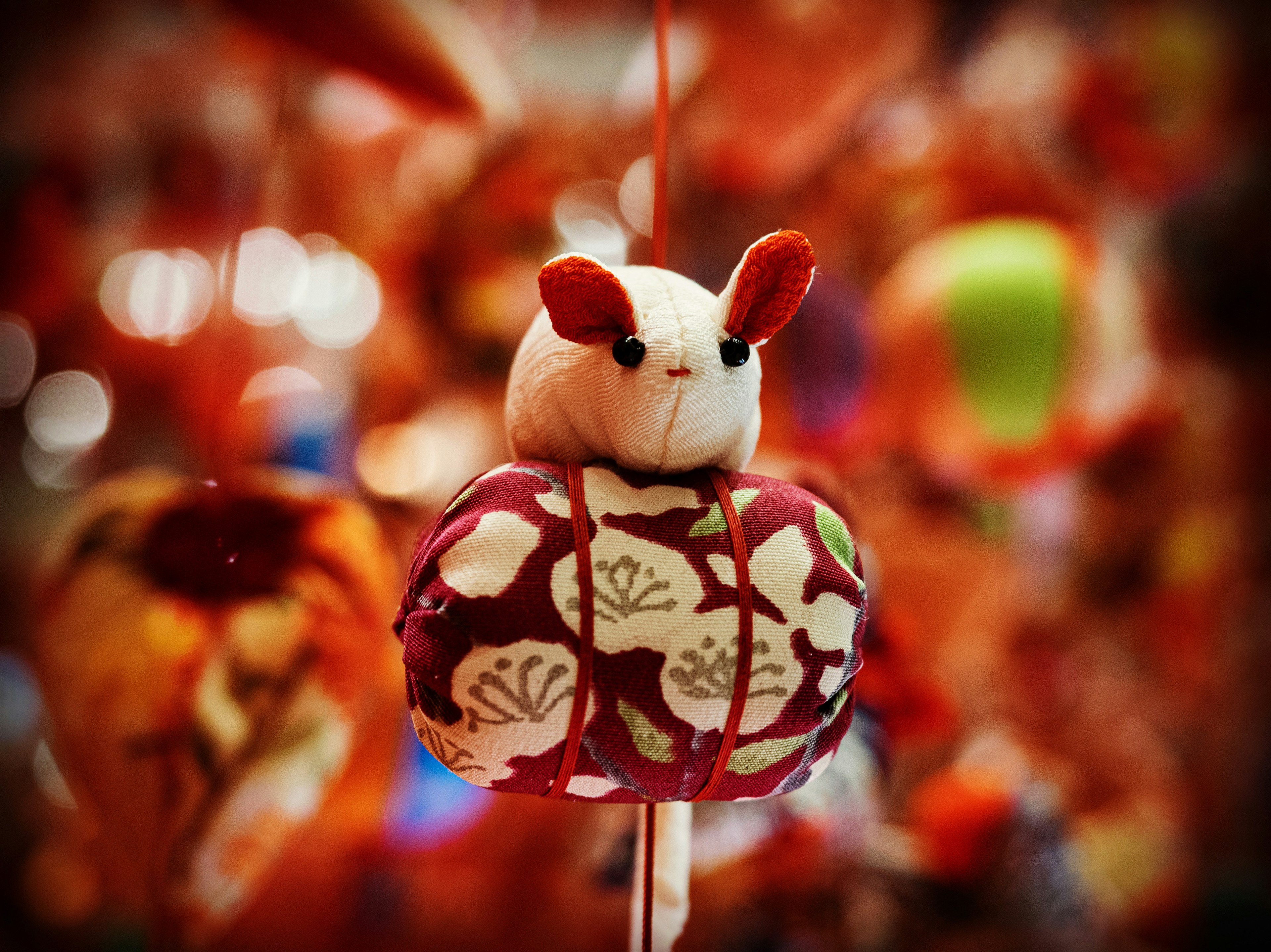 A decorative rabbit figure with a floral kimono hanging against a colorful background