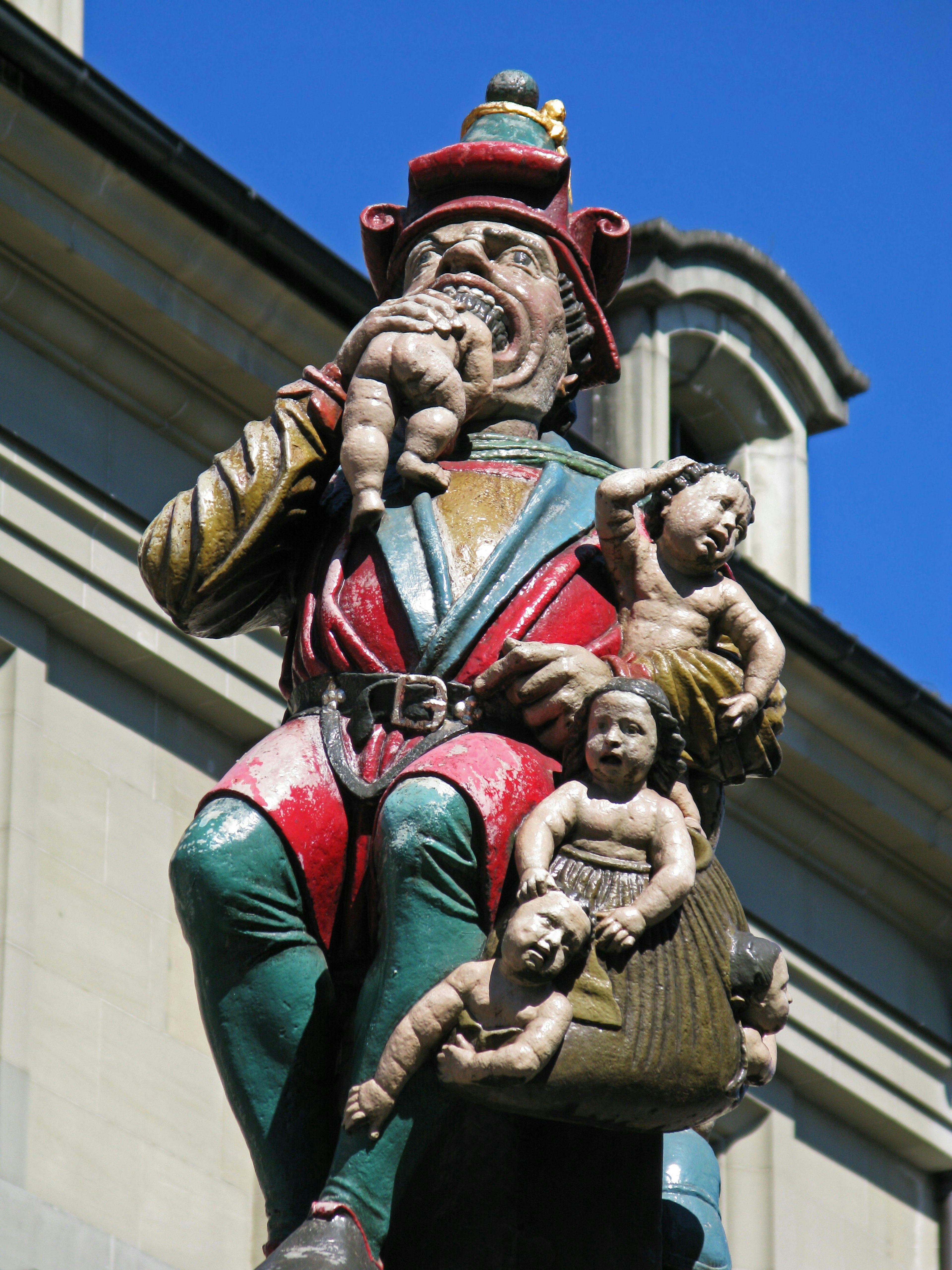 A colorful statue depicting a figure in vibrant clothing holding babies