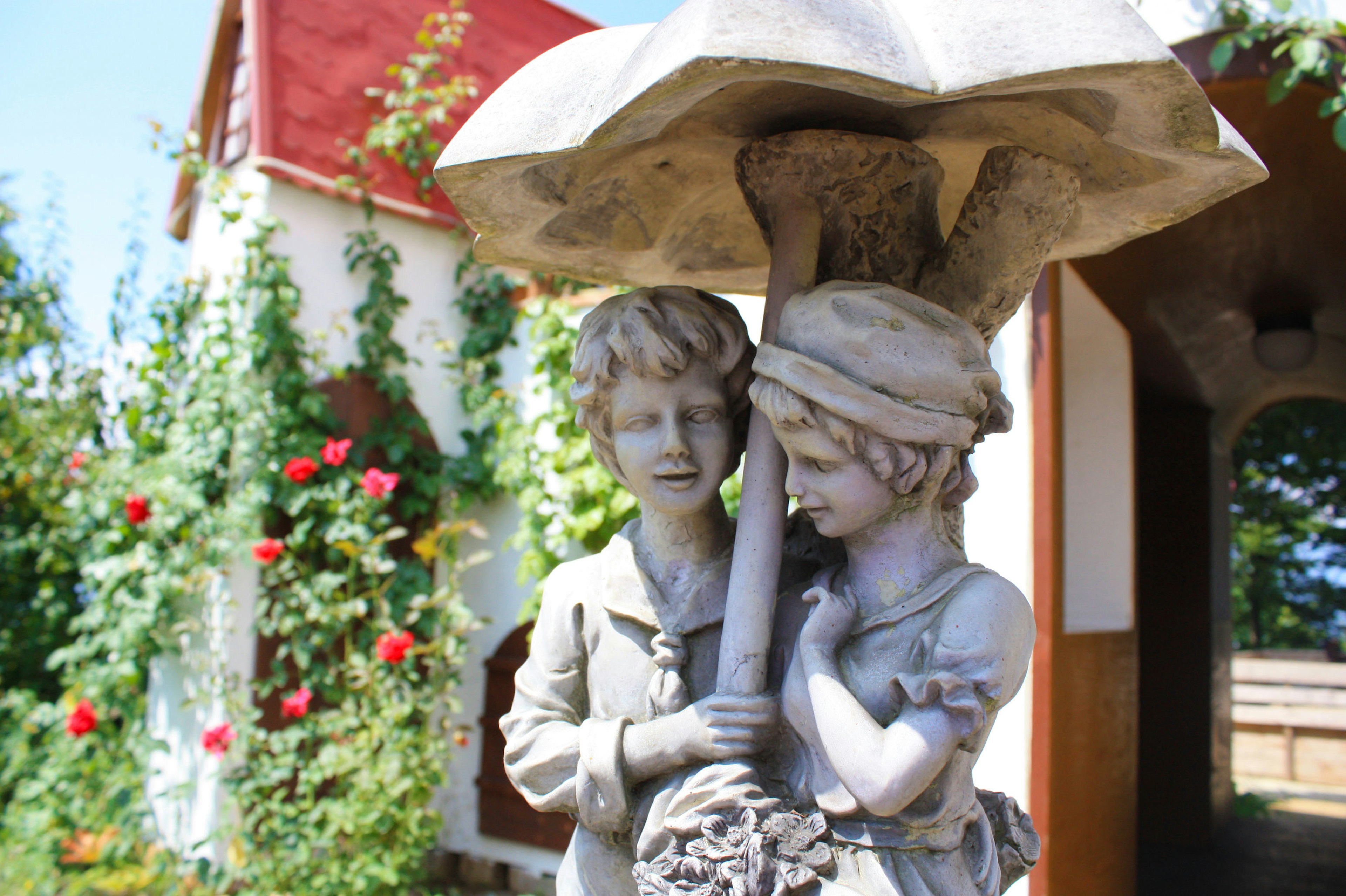 A garden scene featuring a sculpture of children holding an umbrella