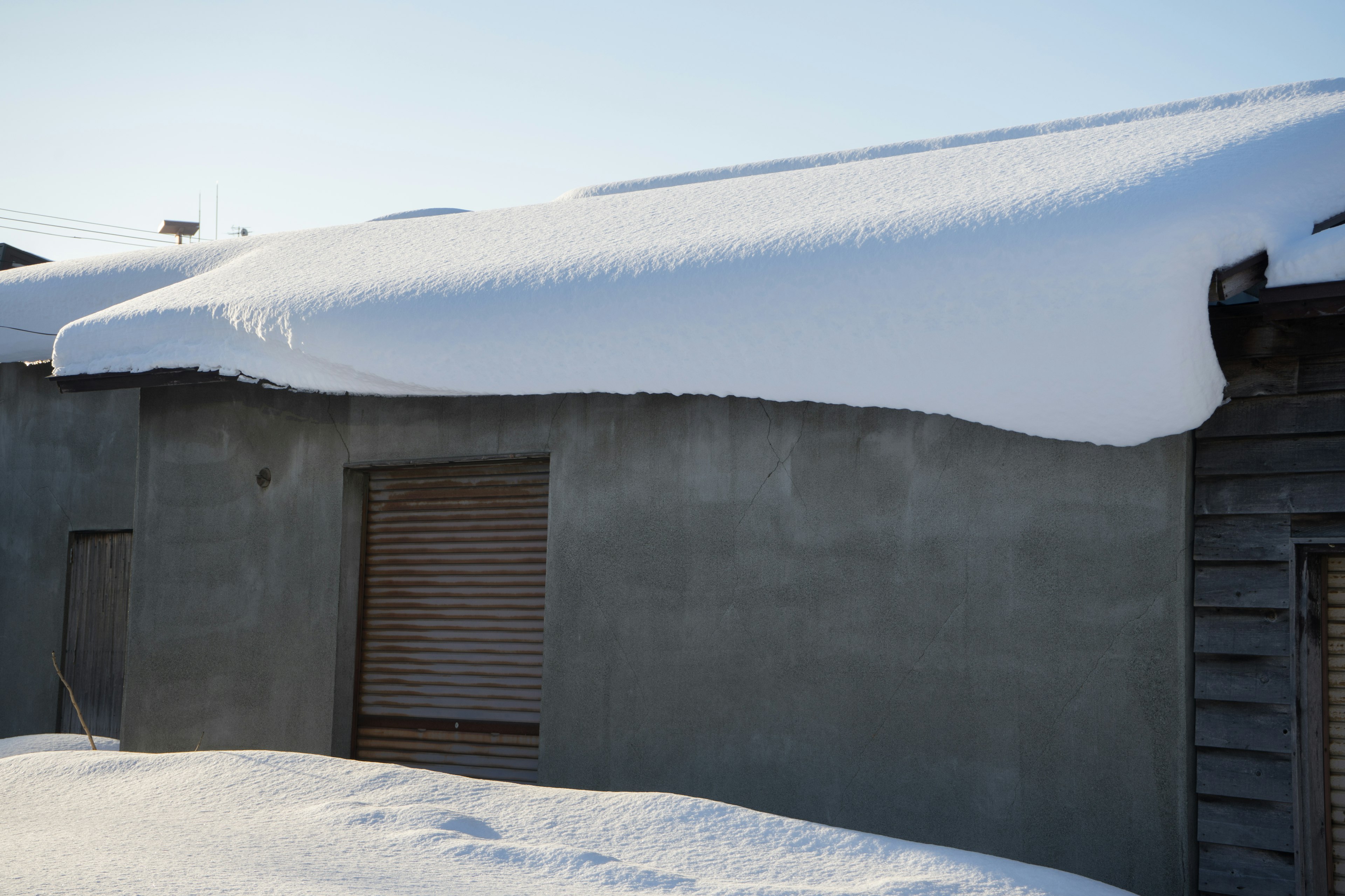 Ein Teil eines Gebäudes mit einem schneebedeckten Dach und einer Außenwand