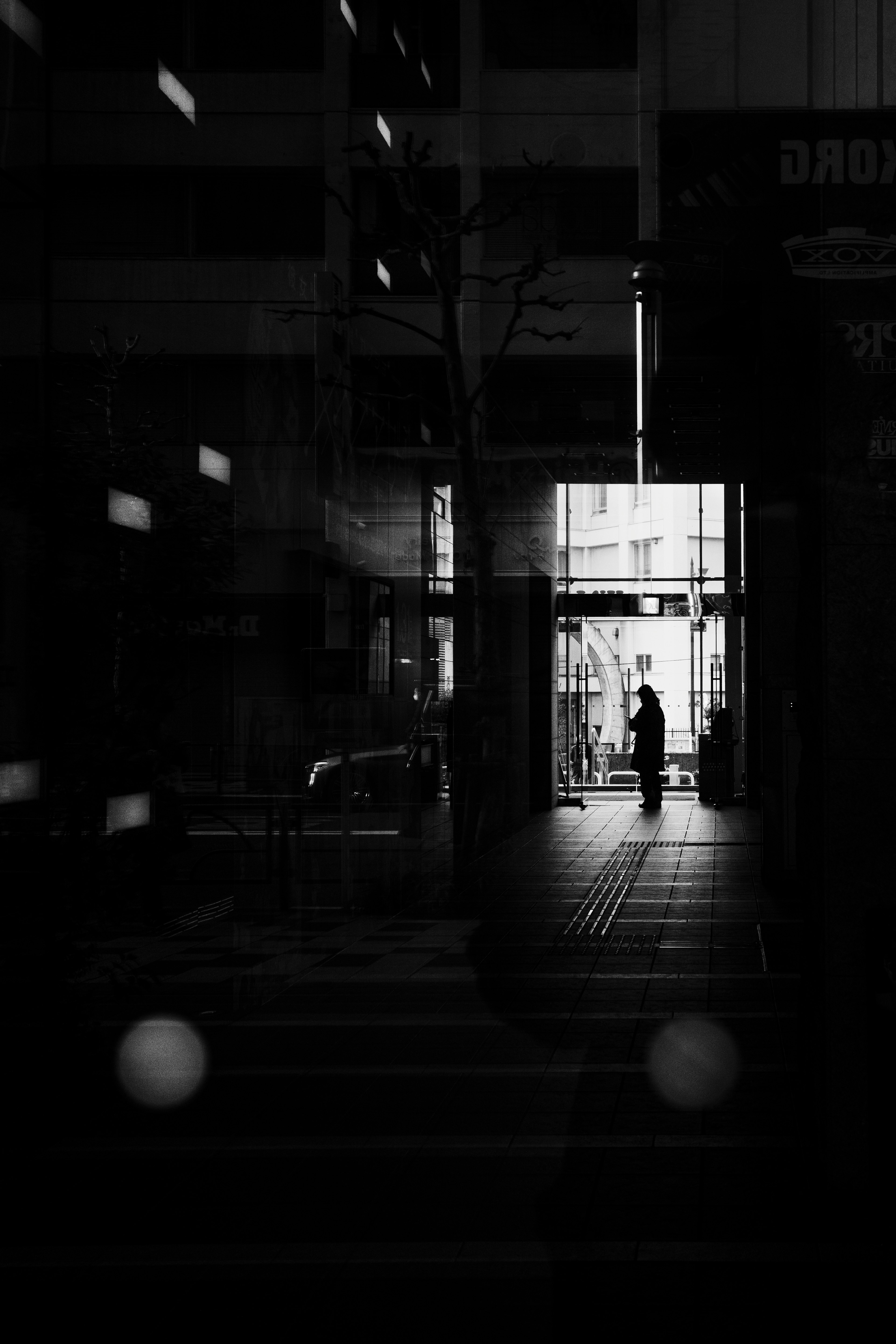 Silhouette of a person standing in a dark corridor with a bright exit