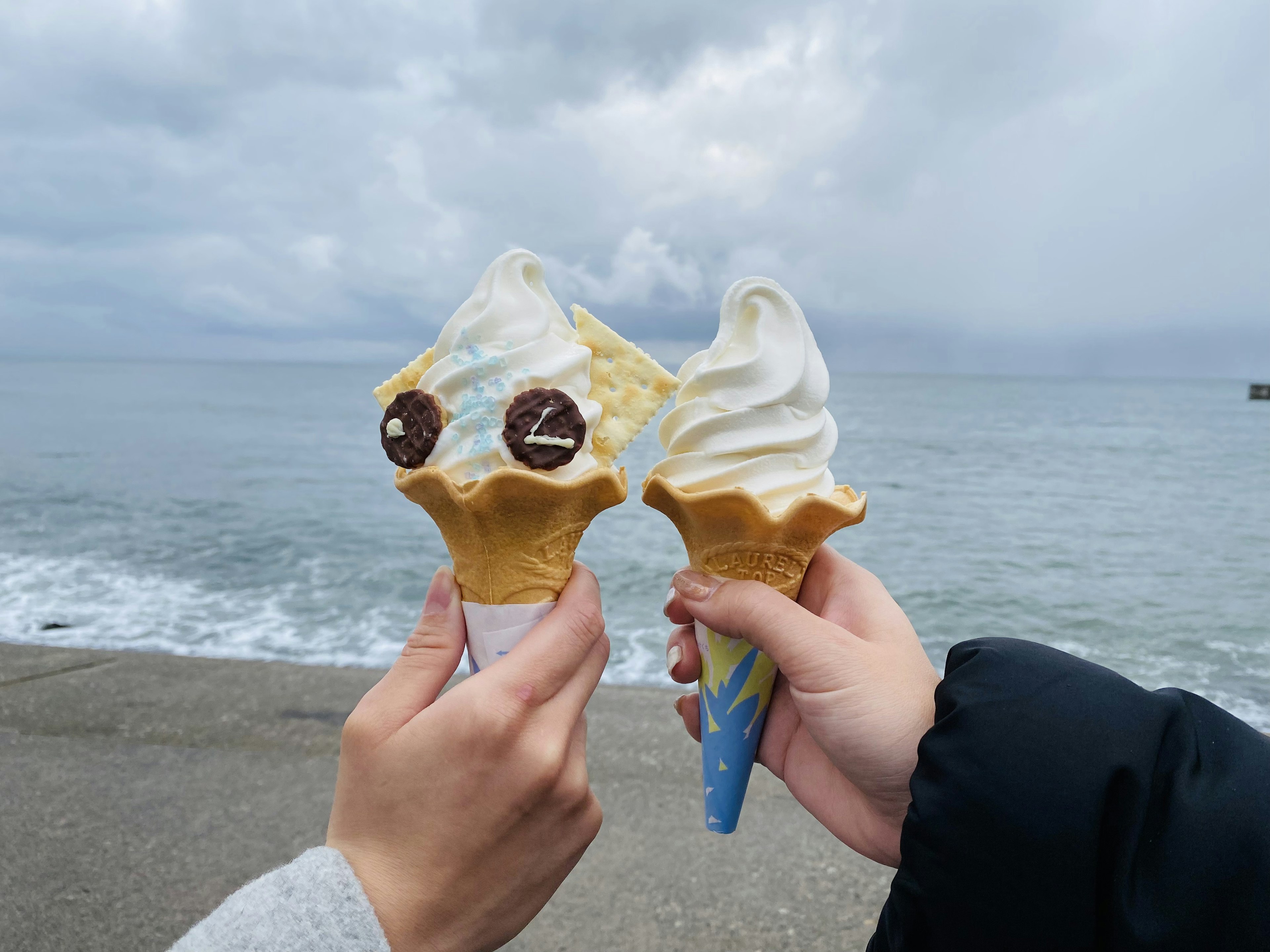 海辺でアイスクリームを持つ二人の手