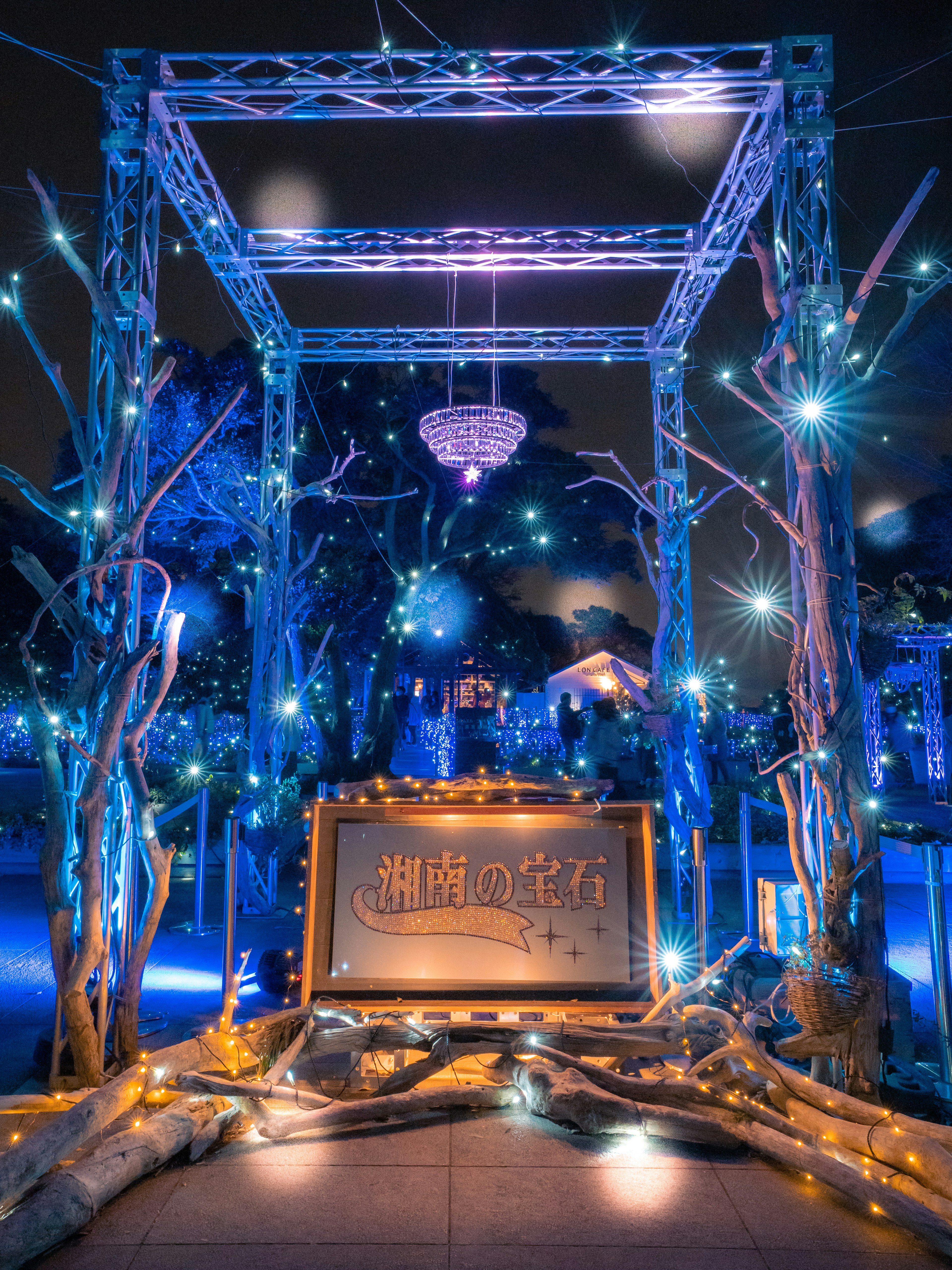 A beautiful arch adorned with blue lighting and decorative branches featuring a chandelier