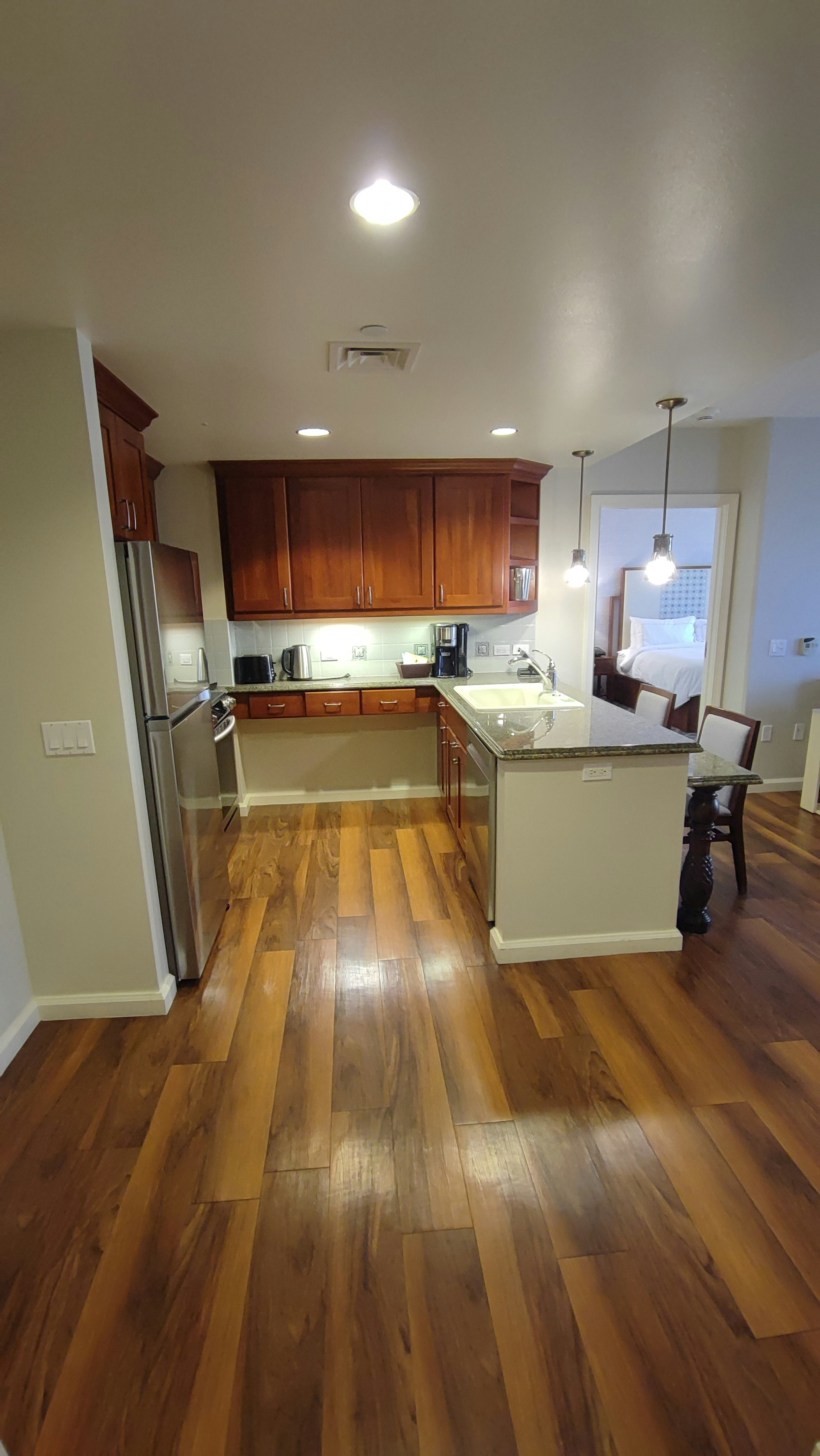 Área de cocina brillante con suelo de madera y gabinetes en contraste