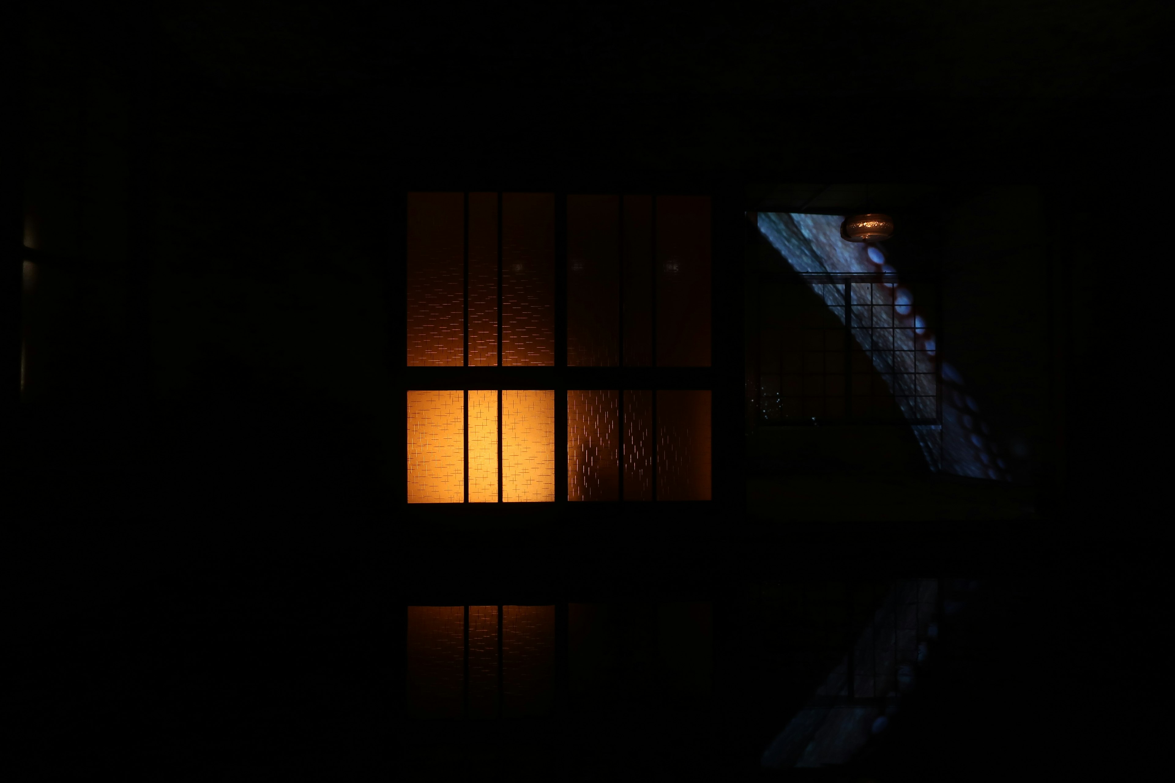 Warme orangefarbene Licht von einem Fenster in einem dunklen Raum mit Treppenschatten