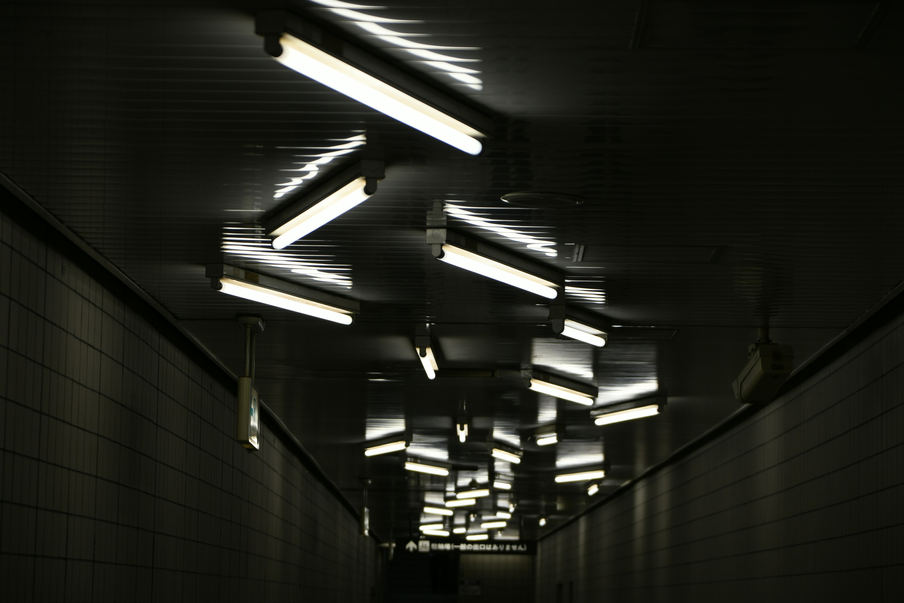 Dunkler Tunnel mit hellen fluoreszierenden Lampen von der Decke hängend