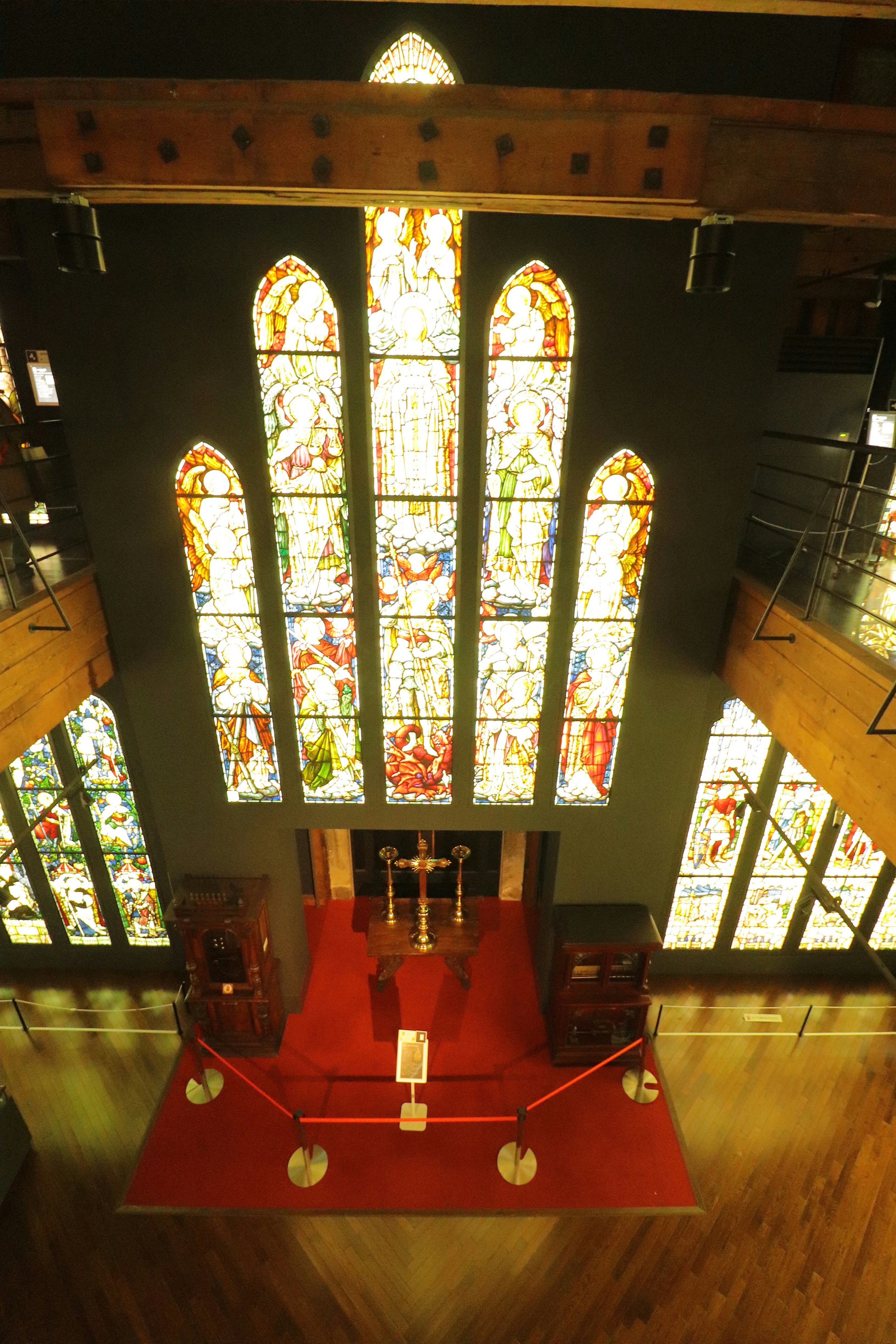 Vista interior de una iglesia con grandes vitrales alfombra roja que conduce al altar