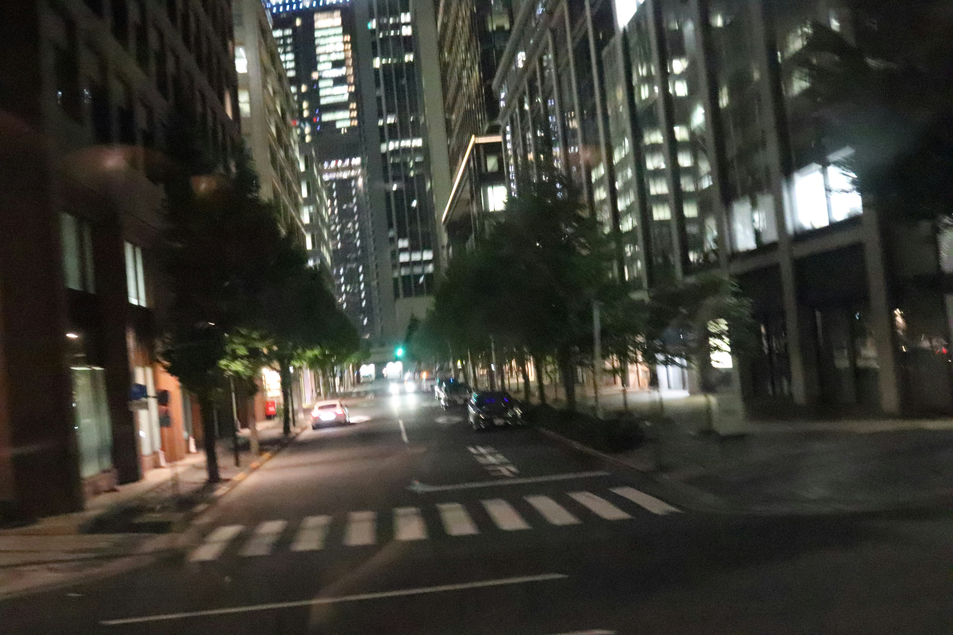 Rue urbaine nocturne avec de grands bâtiments et passage piéton