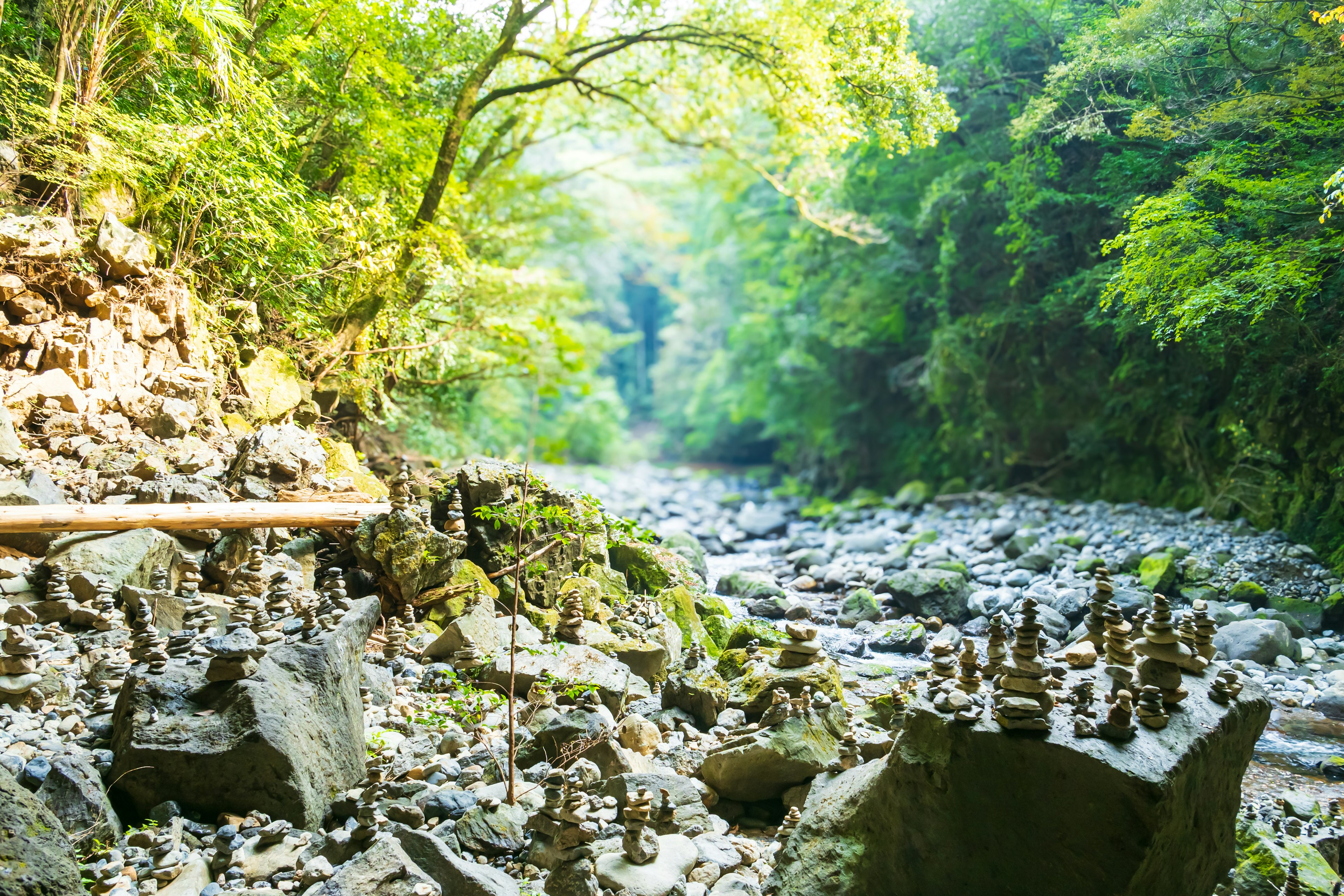 A serene riverbank featuring stacked stone towers and lush greenery