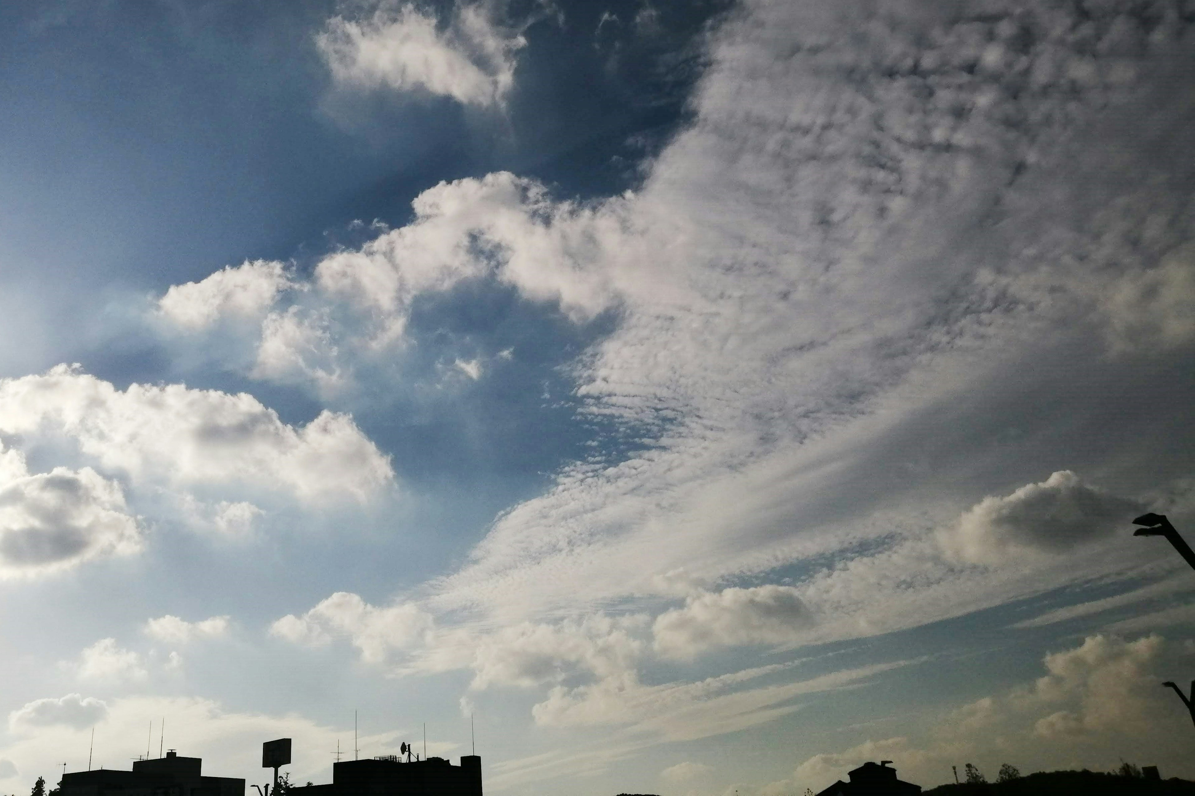 Langit biru dengan awan putih dan siluet bangunan