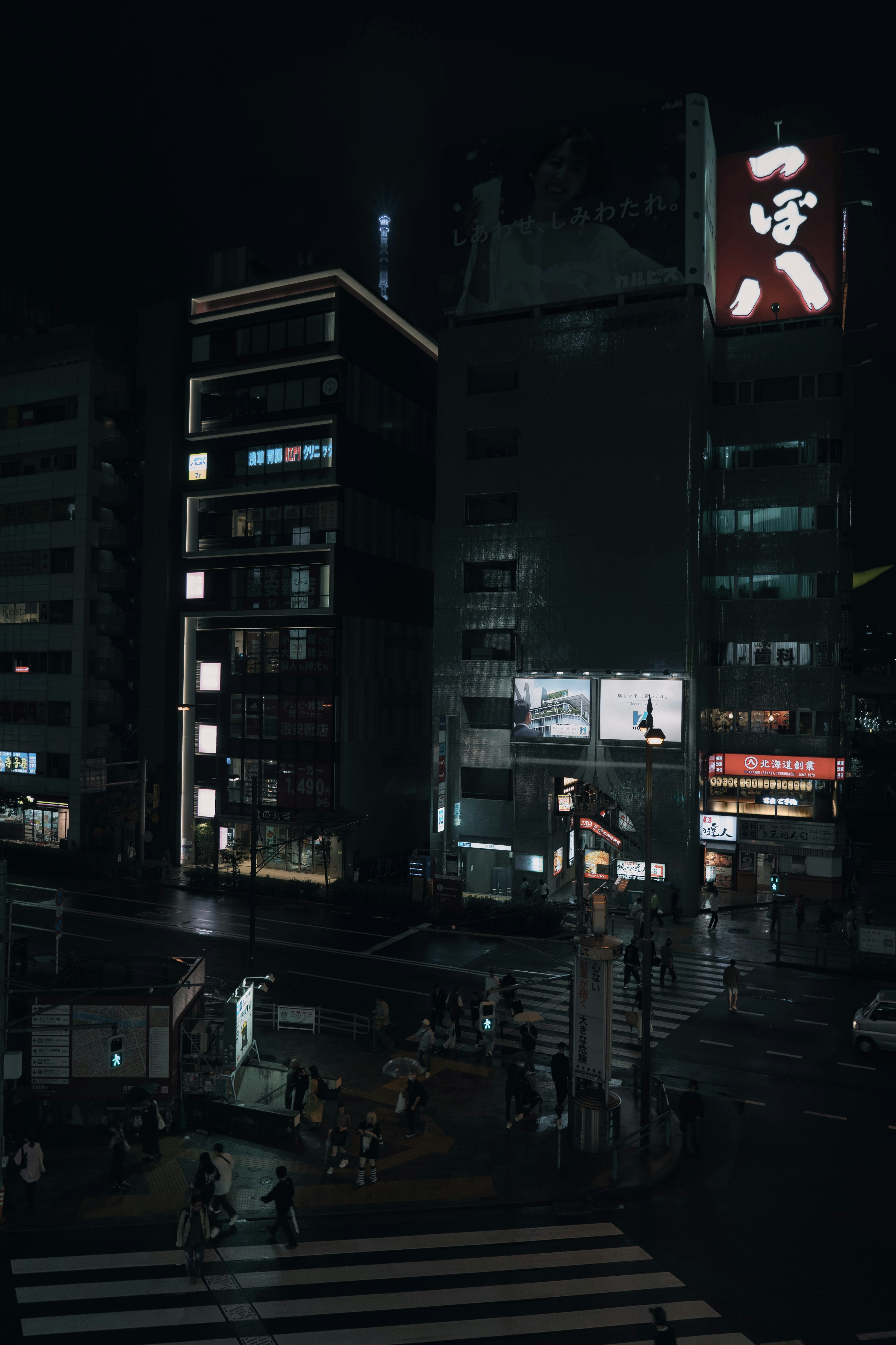 Paysage urbain nocturne avec des enseignes lumineuses et des personnes traversant l'intersection