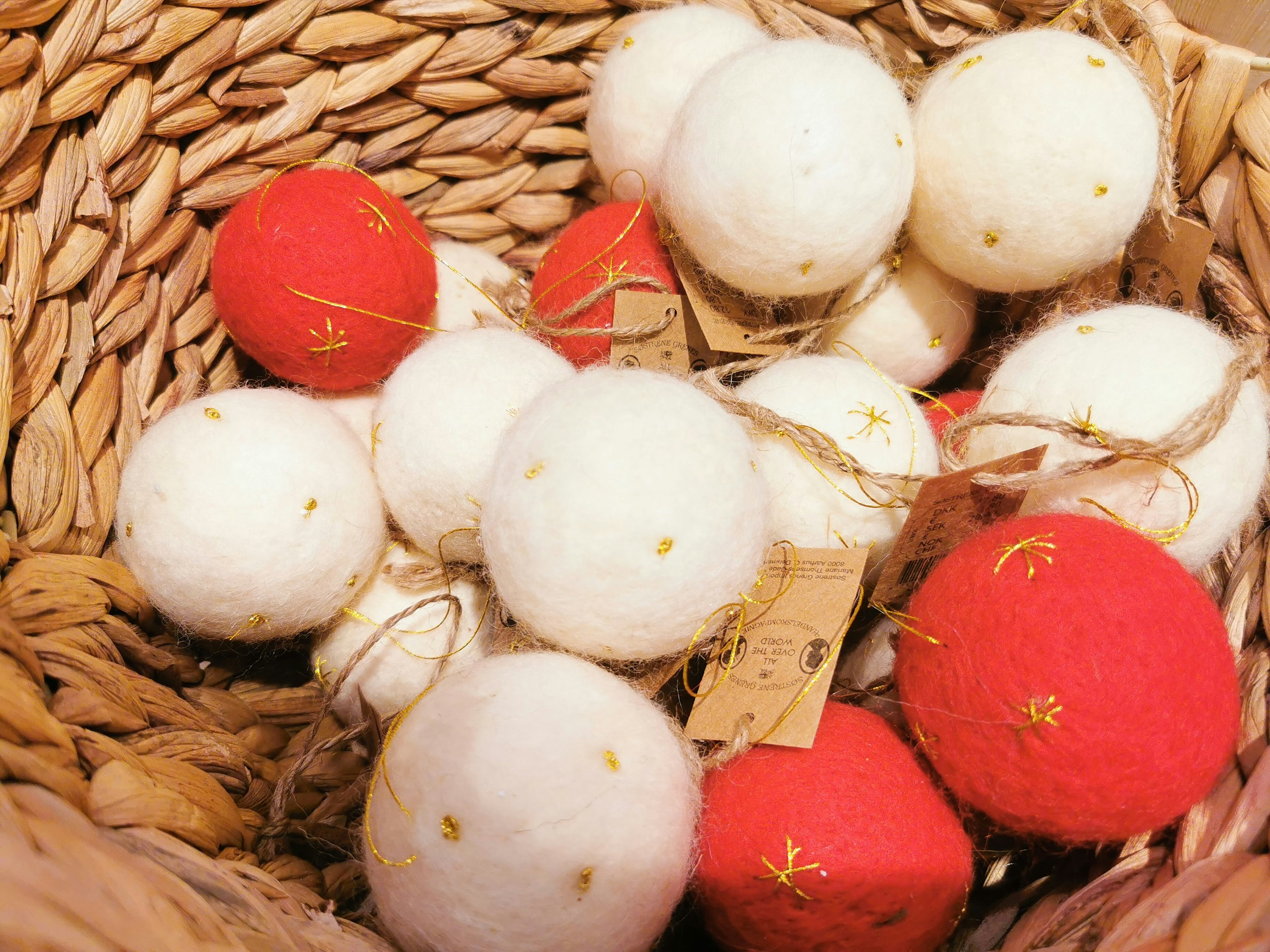 A basket filled with red and white felt balls adorned with decorative stitching