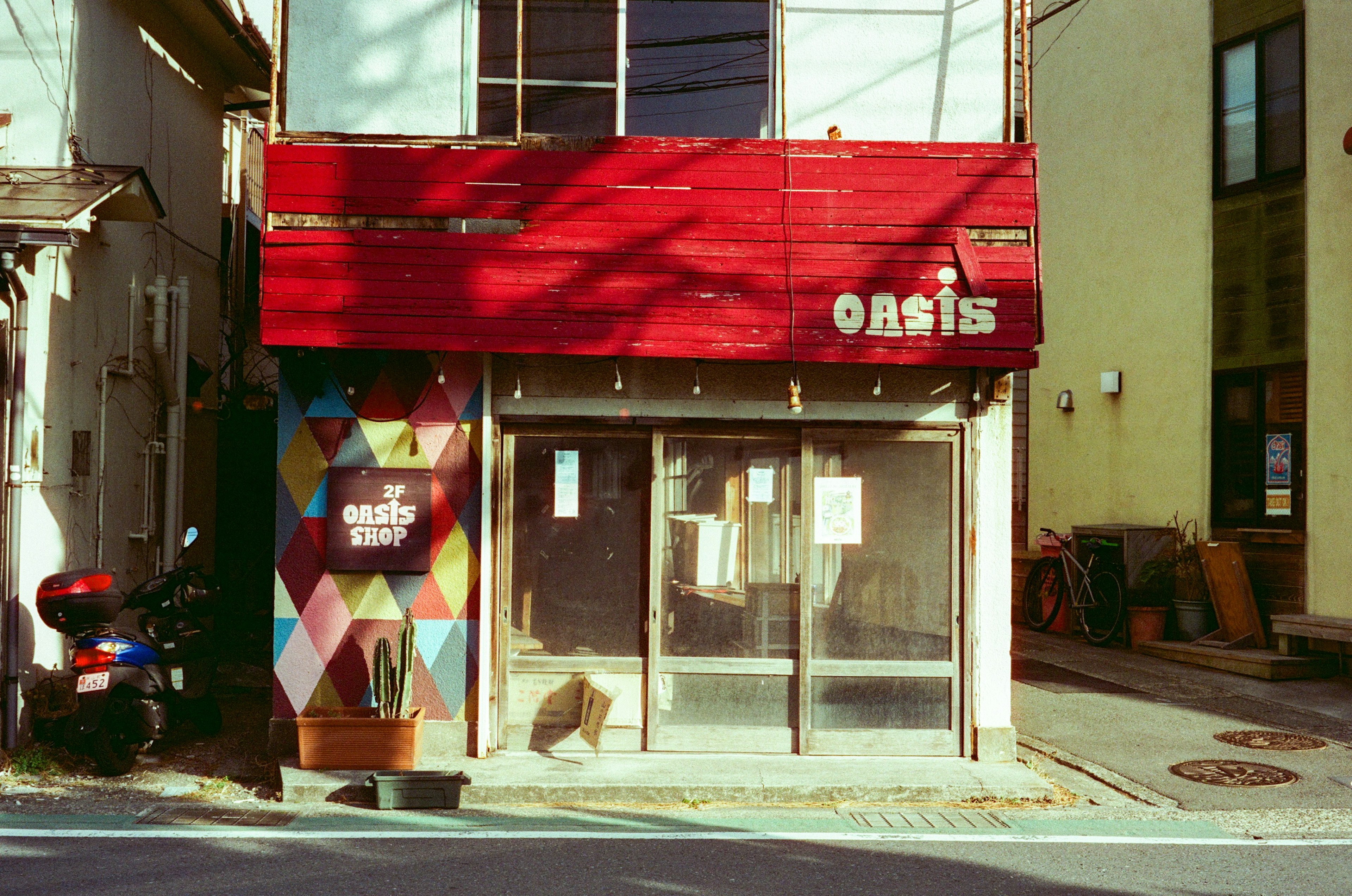 Vista de una calle de una tienda llamada Oasis con un exterior rojo y patrones geométricos coloridos