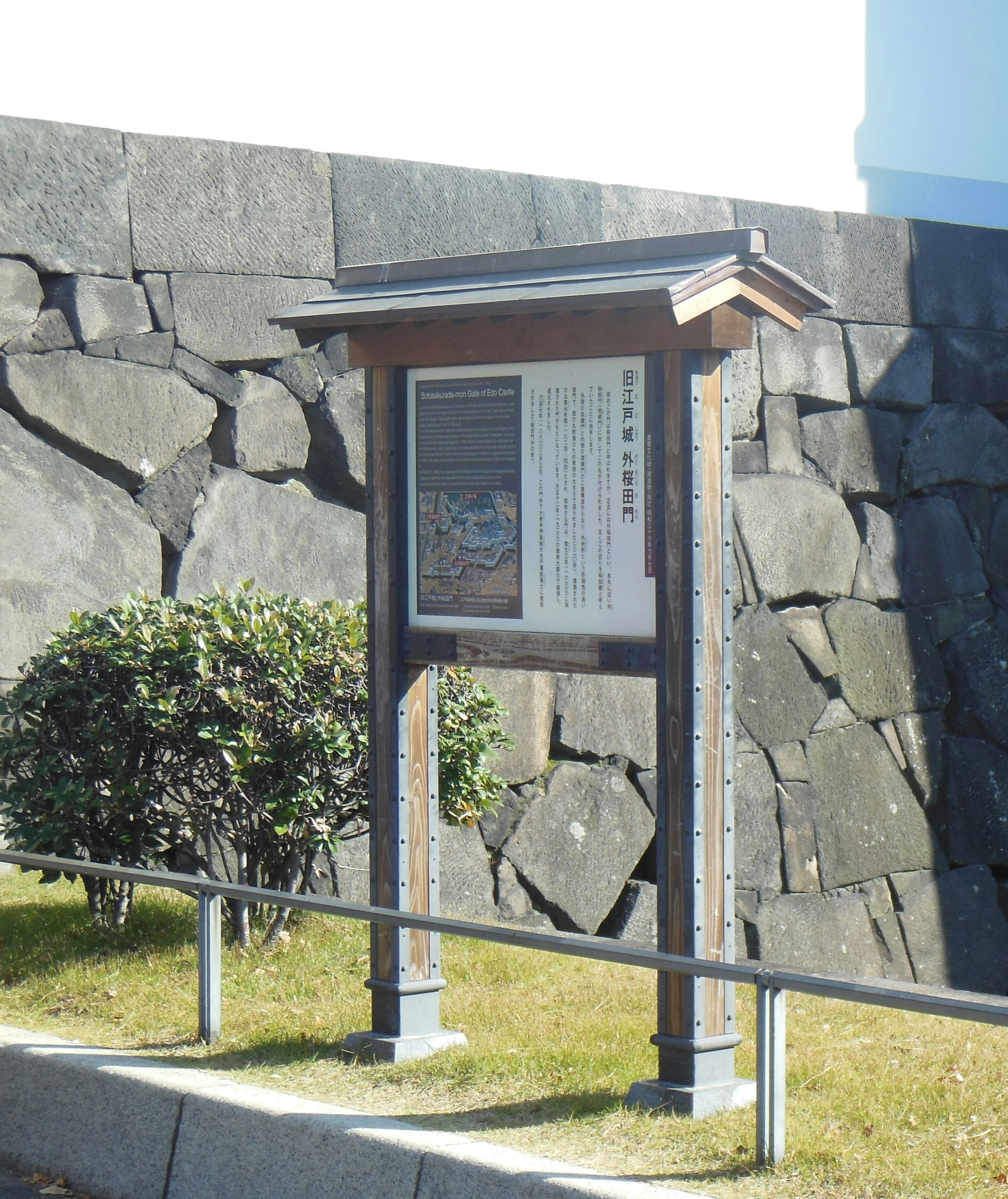 Señal histórica frente a una pared de piedra con marco de madera y texto descriptivo