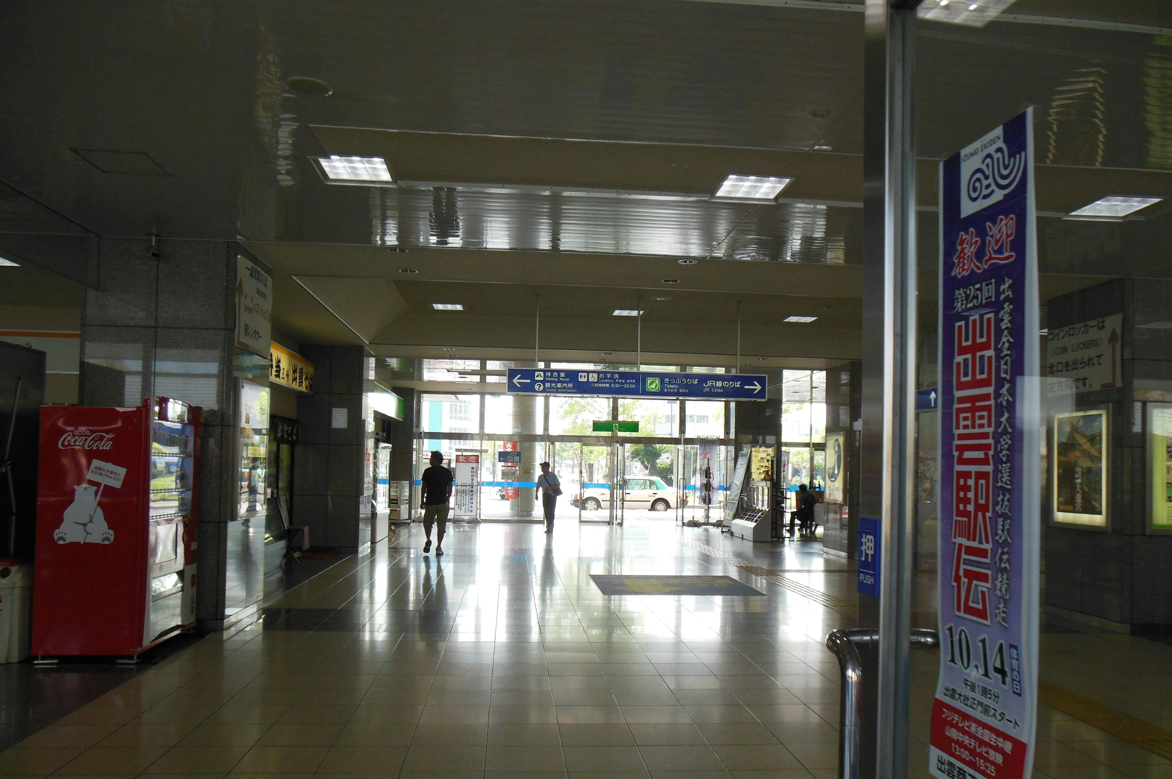 Interior view of a train station people walking towards the exit bright lighting and spacious area