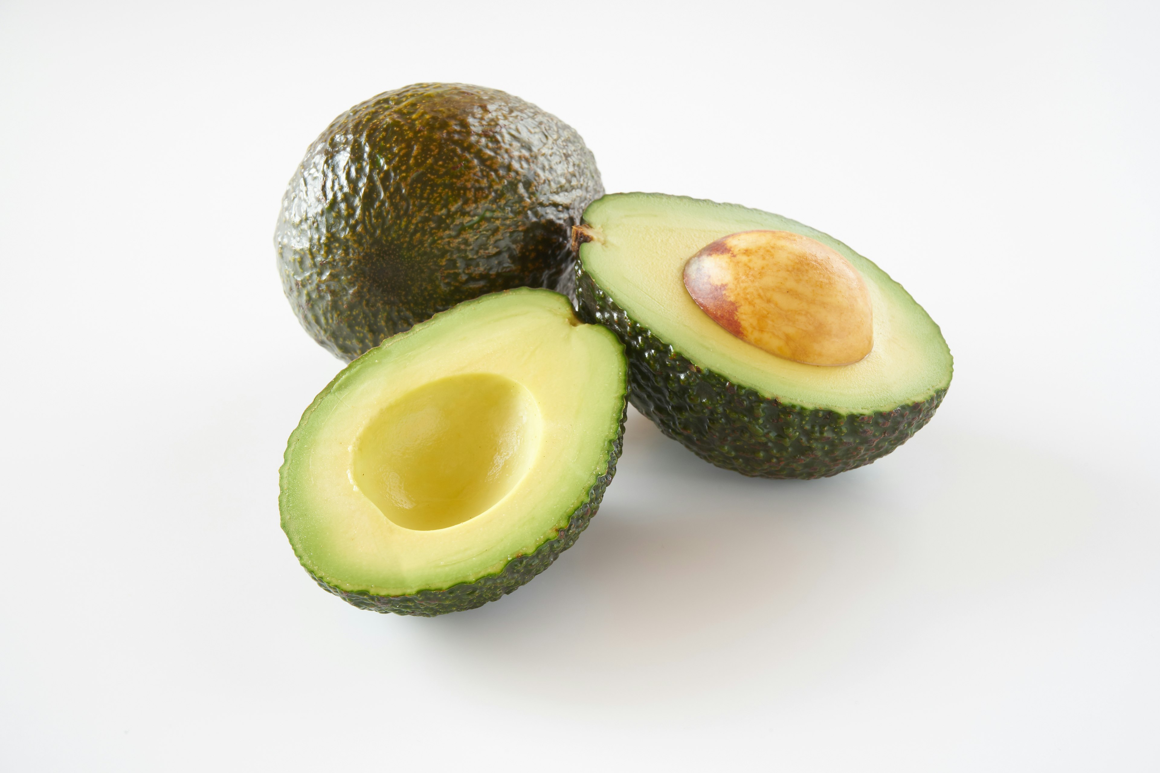 Whole and halved avocados on a white background