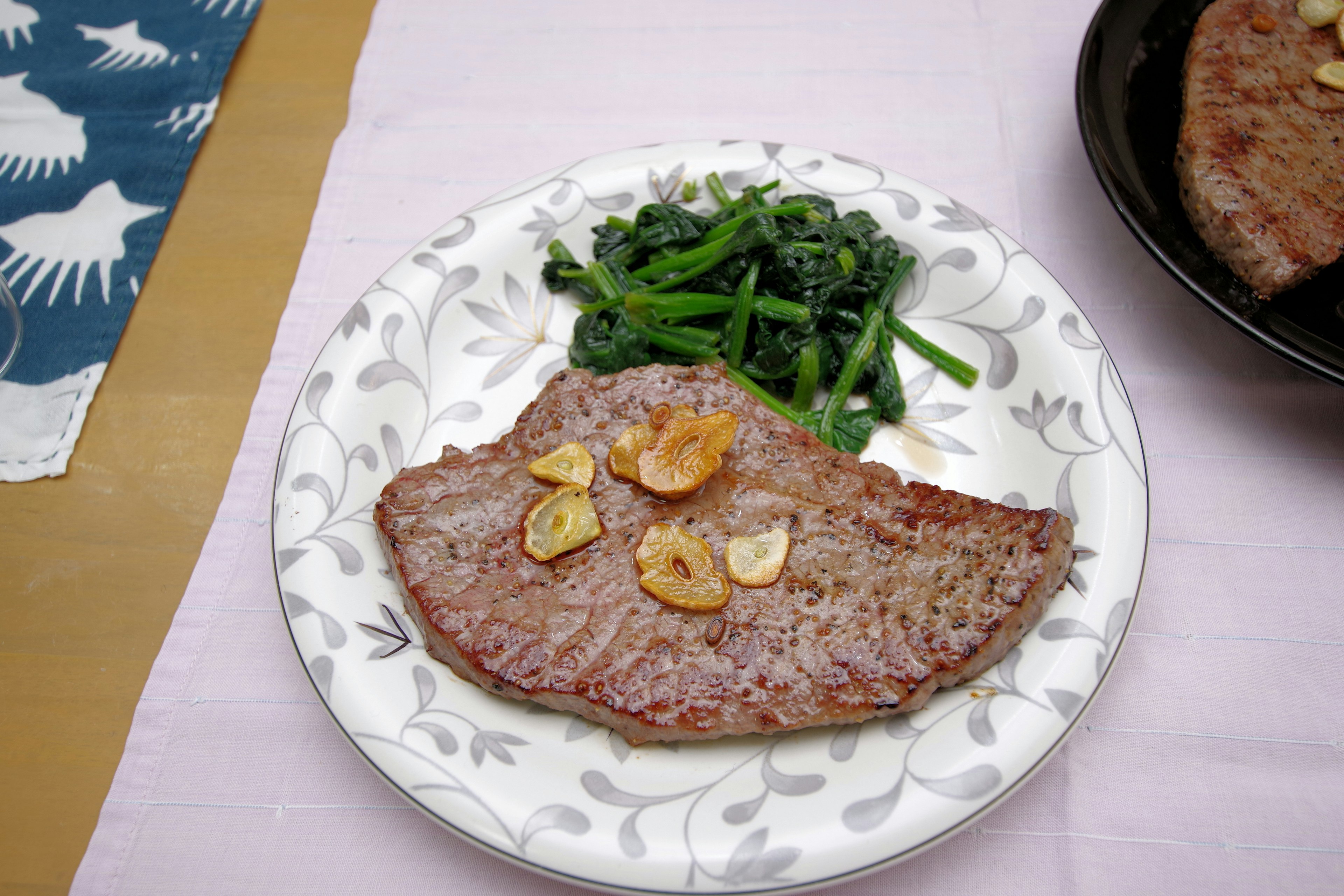 Piatto di carne cotta con fette d'aglio e verdure verdi di lato