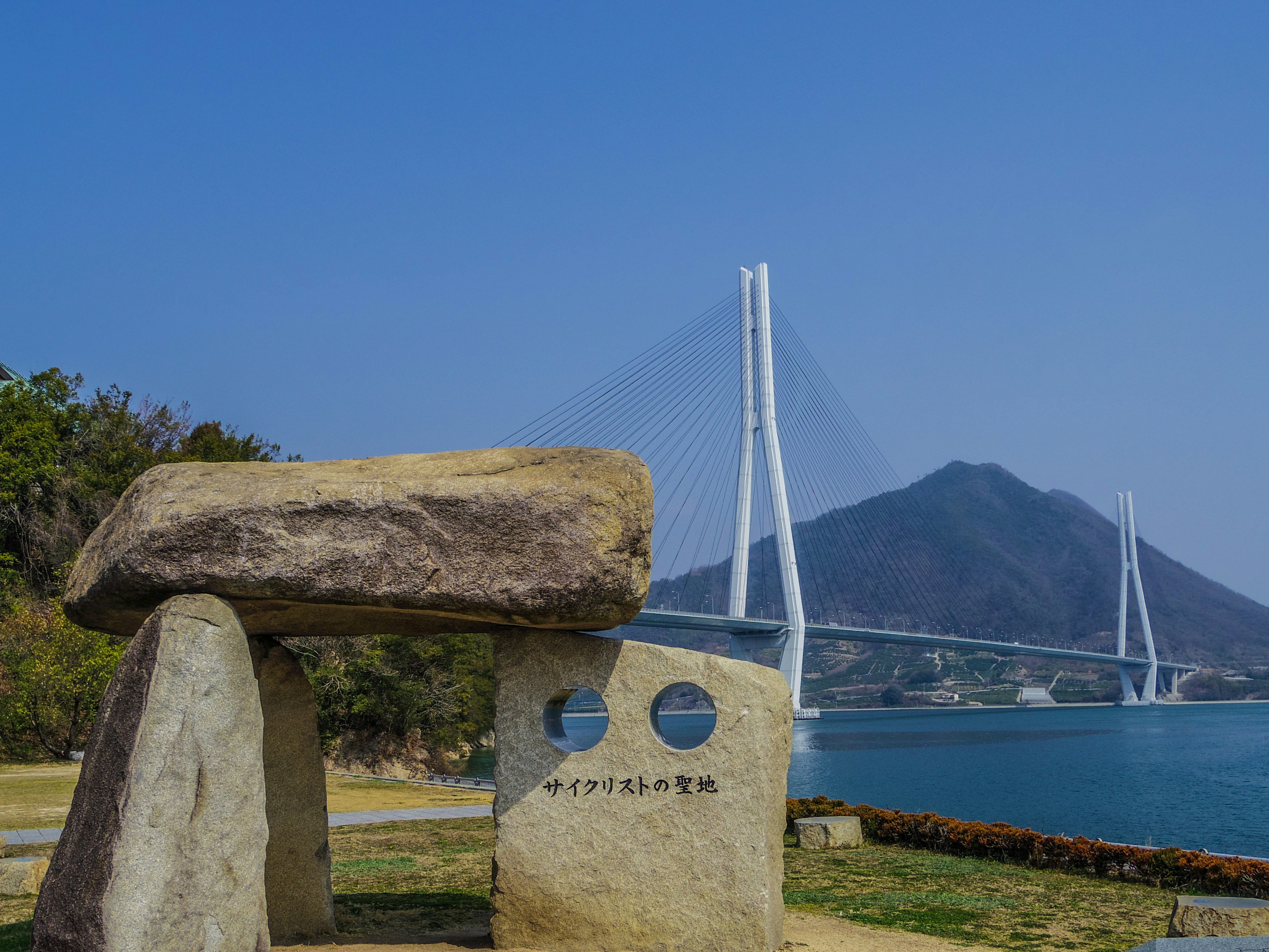 Stone sculpture and monument with a bridge and mountain in the background