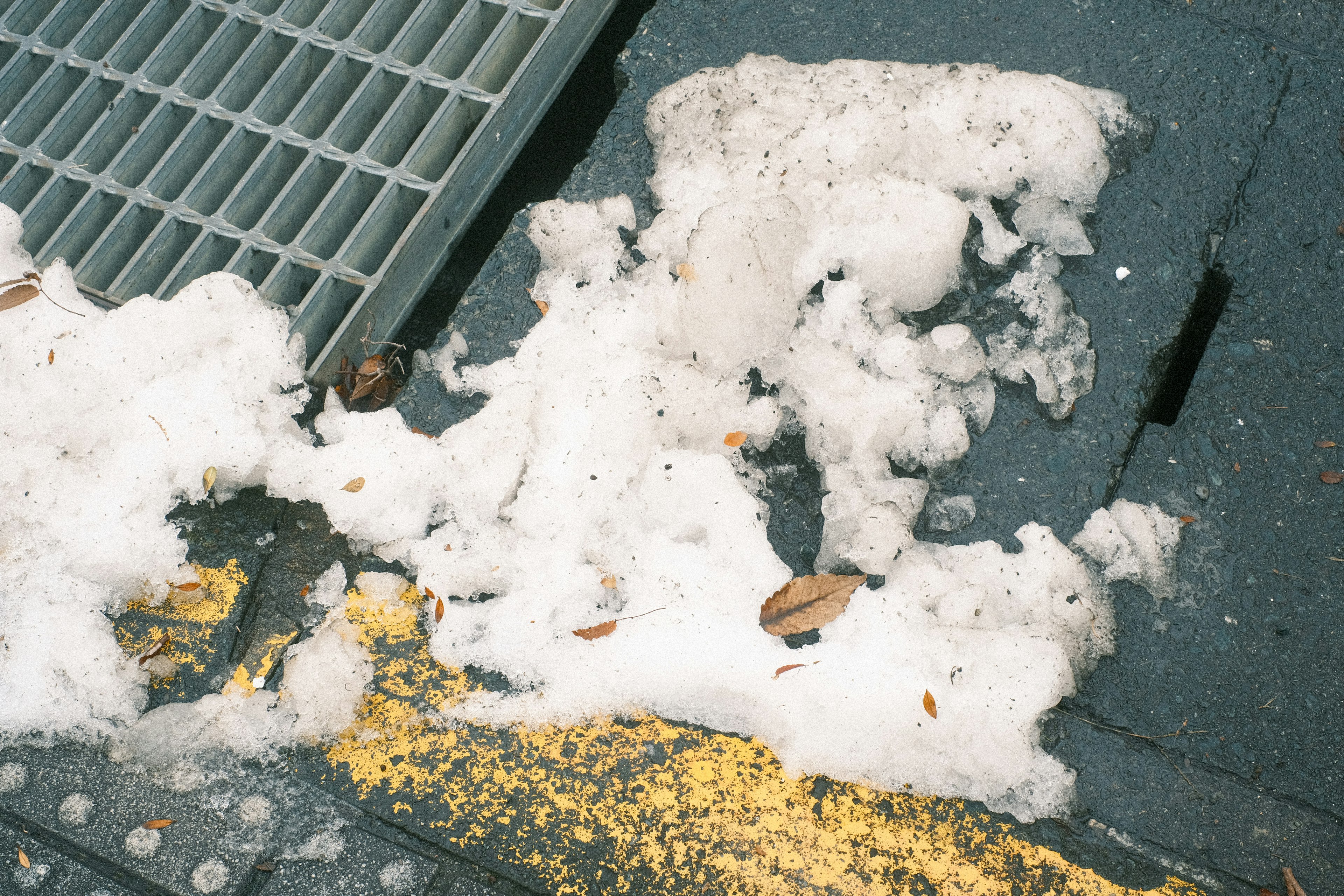 道路の側溝の近くにある白いゴミと黄色の線