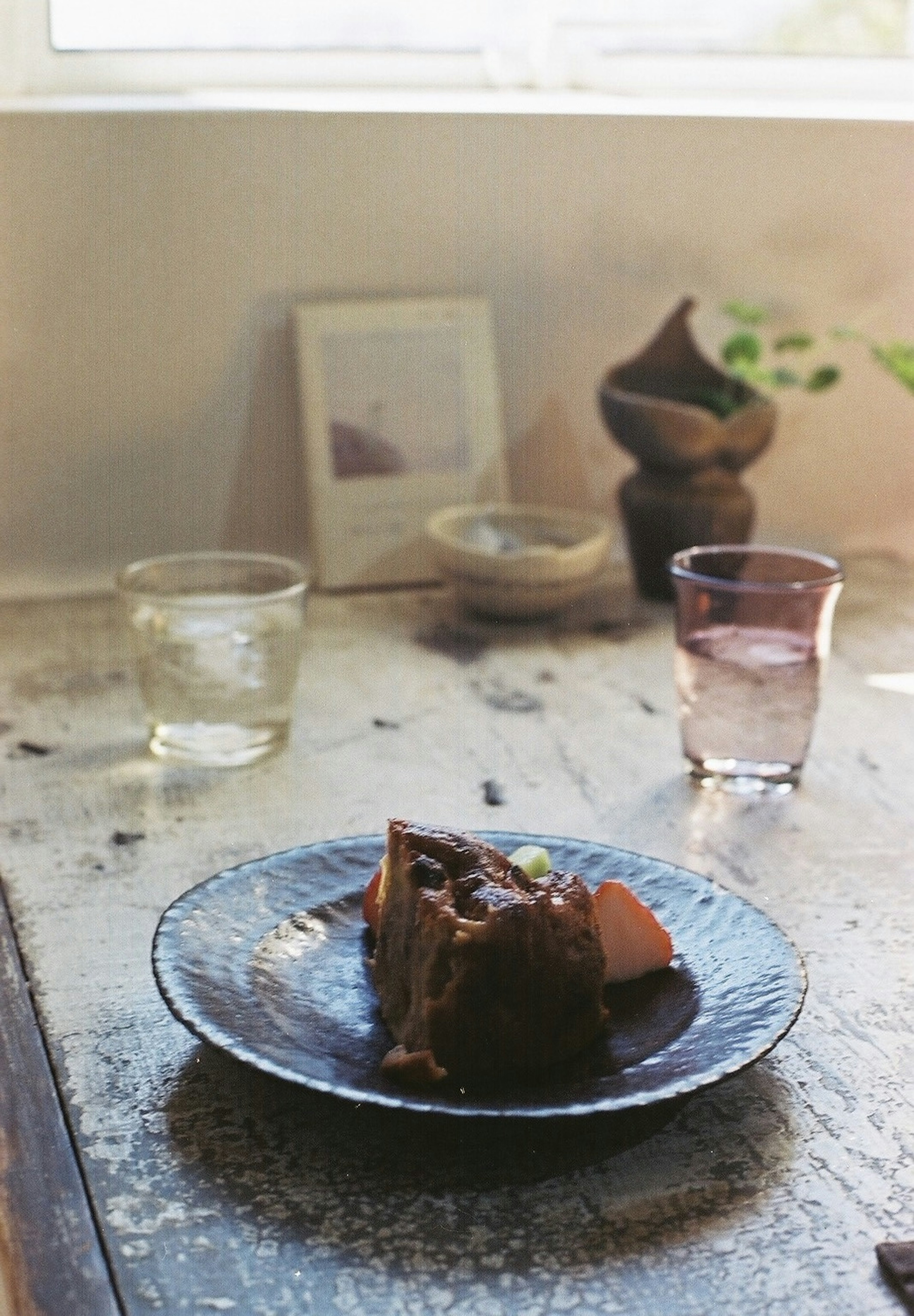 A delicious dessert on a plate with transparent drinking glasses on a rustic table