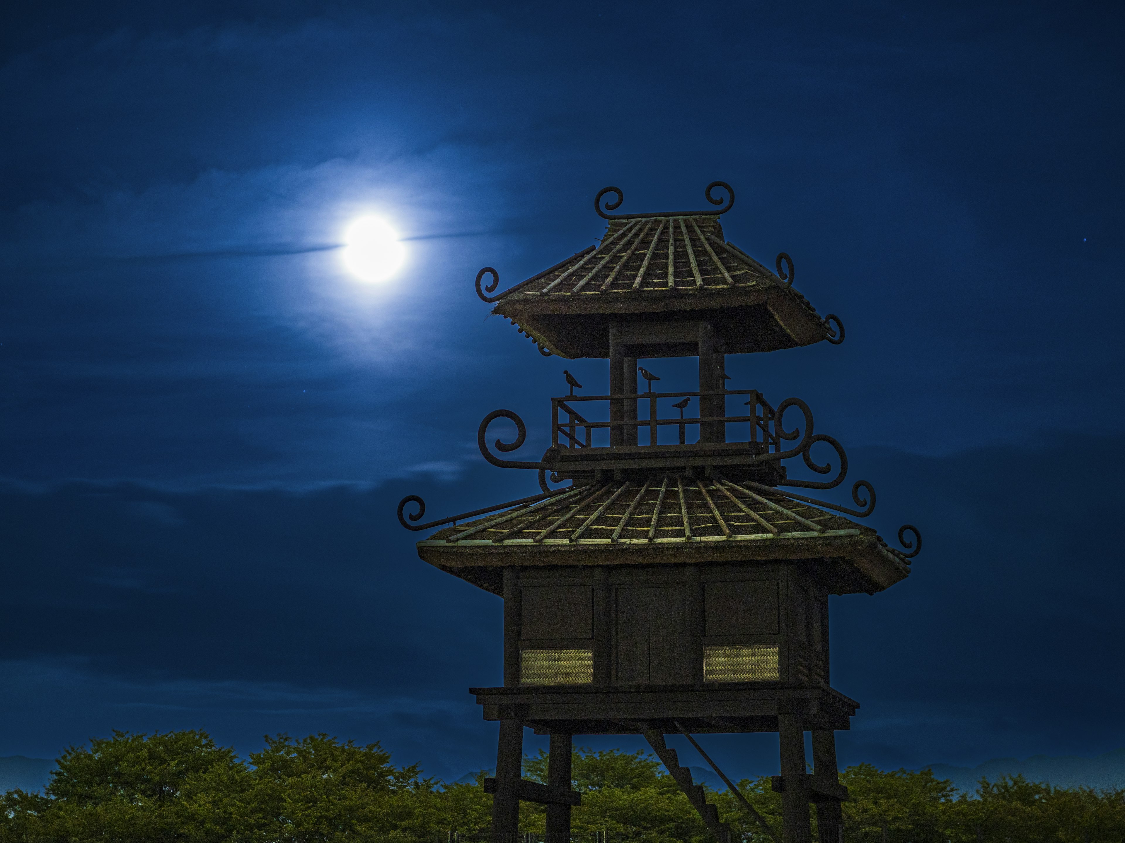 Traditional tower under moonlight with a blue sky