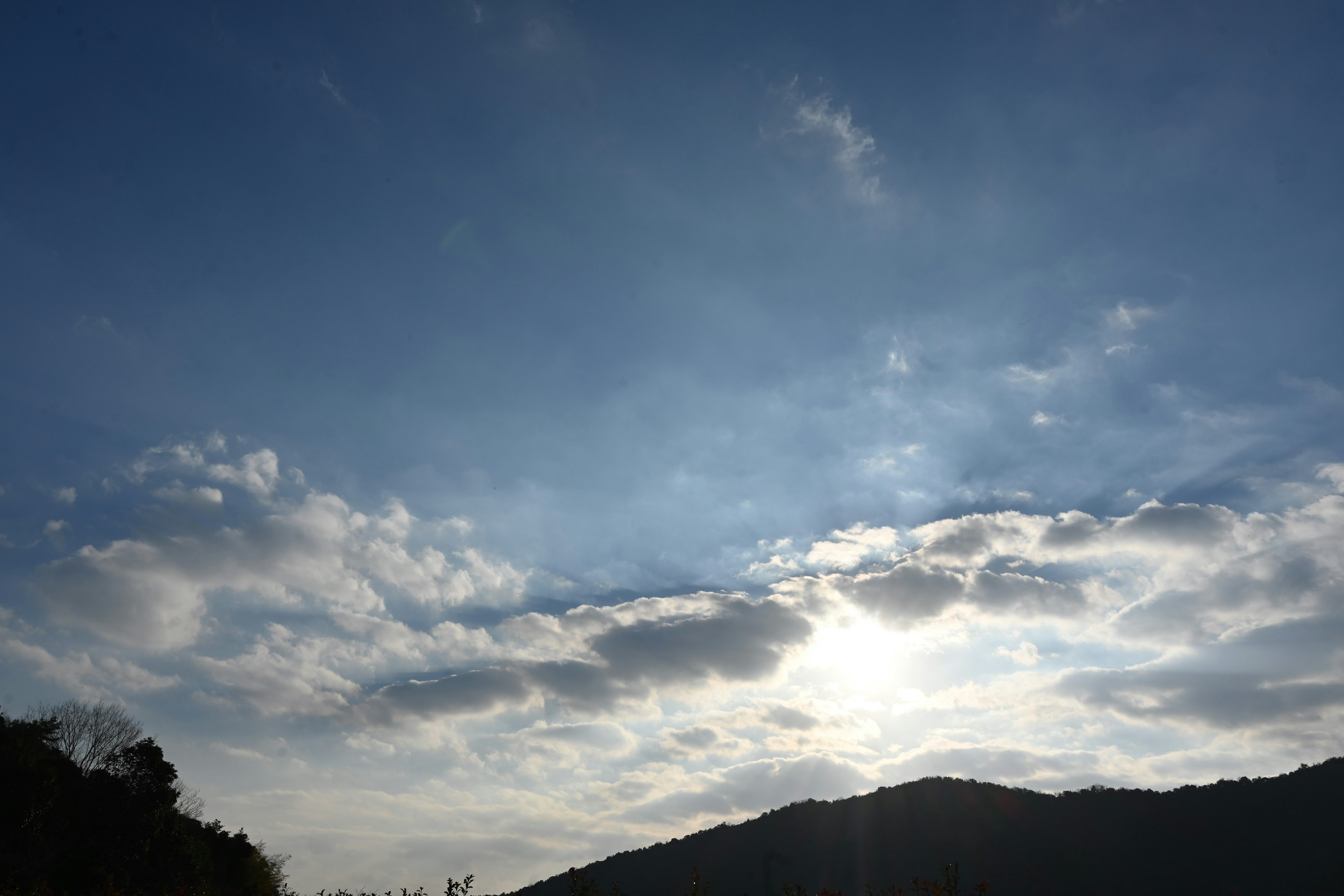 Cielo azul con nubes blancas y silueta de montaña